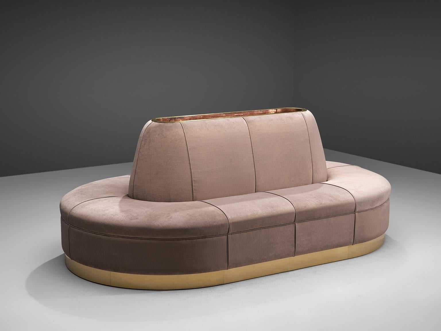 Oval sofa, velvet, brass, Italy, 1970s

This oval shaped sofa is arranged around a center piece with integrated storage space. At the bottom from a gold colored brass base the velvet upholstery starts its way upwards. The upholstery is structured in