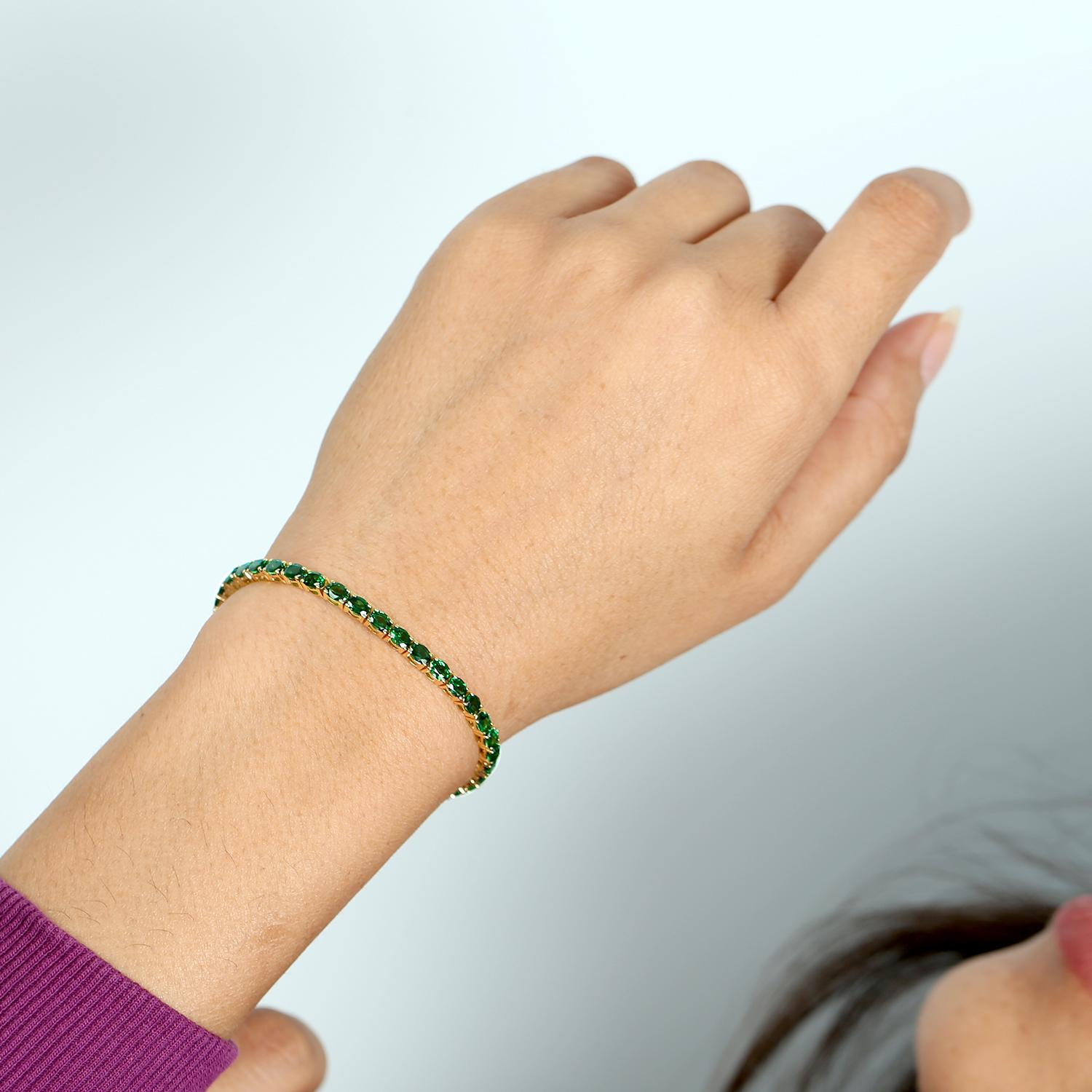 The Oval Shaped Tsavorite Tennis Bracelet is an exquisite piece of jewelry crafted in luxurious 18K yellow gold. It features a continuous row of vibrant, oval-cut tsavorite gemstones, each meticulously set to showcase their rich green hues.