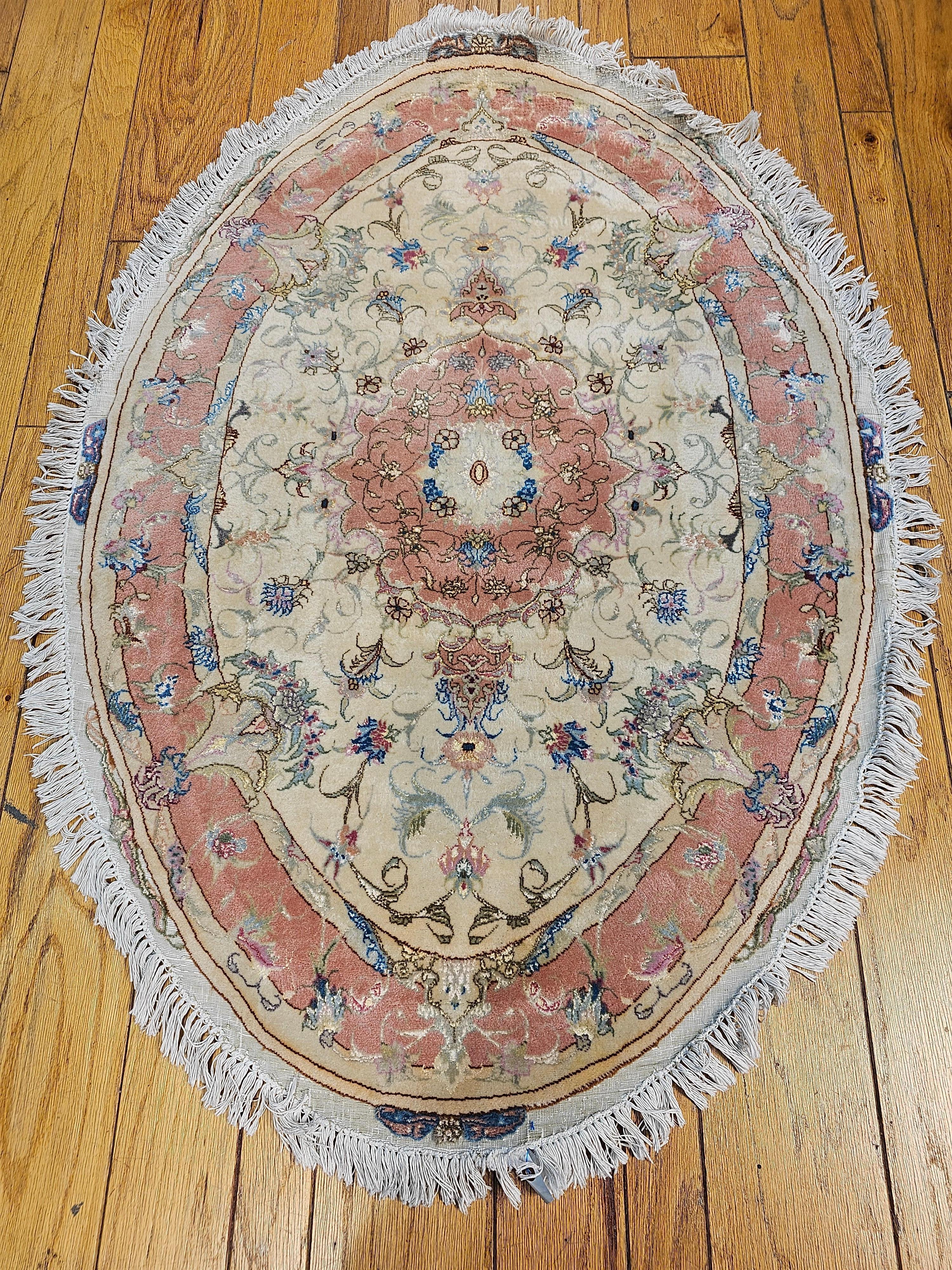 A rare and very desirable oval shape Persian Tabriz Area Rug in floral pattern with silk highlights in pastel colors from the 4th quarter of the 1900s. The rug has a floral design set in a cream color field with a pale salmon/pink color border.  