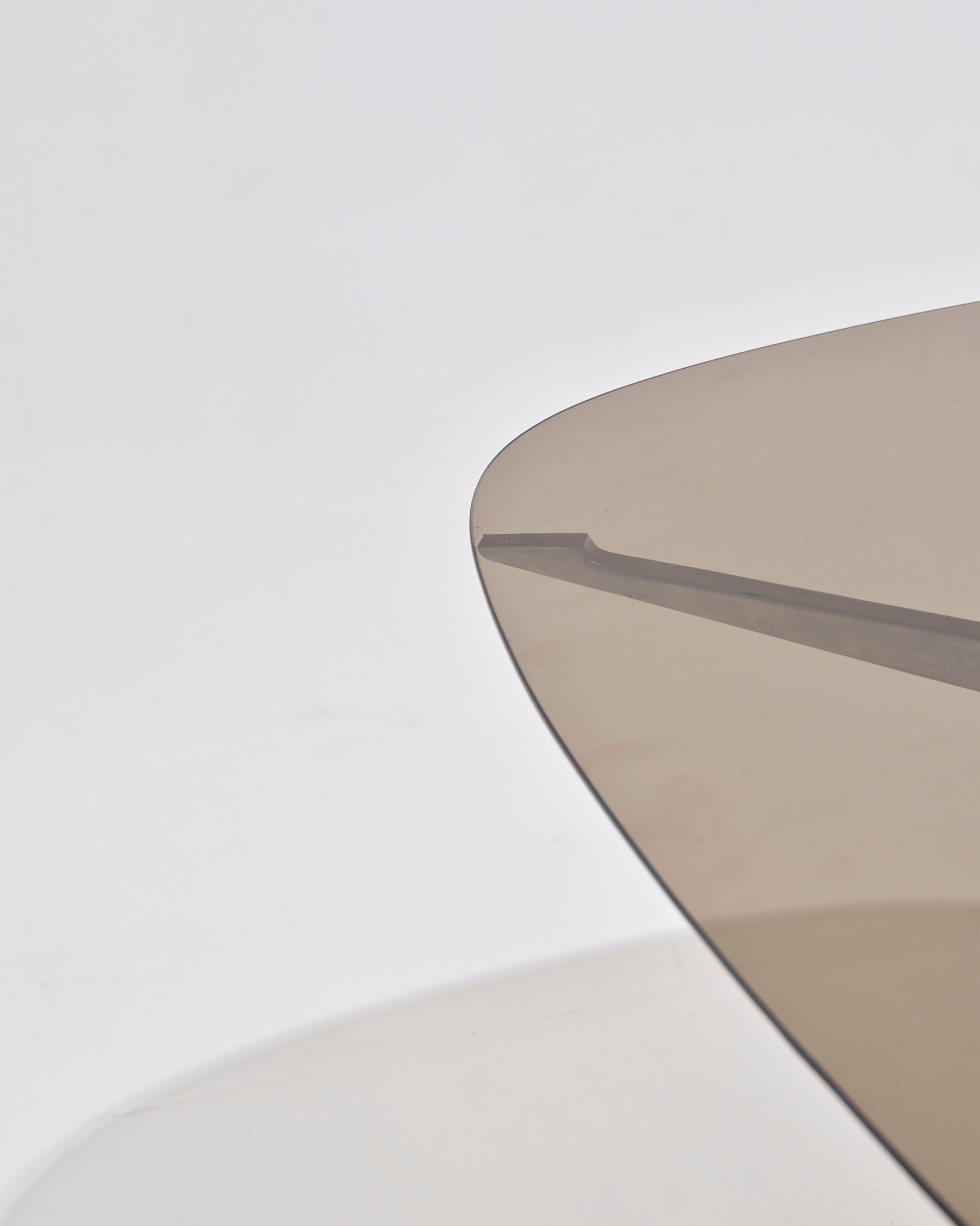 Oval dining table in glass and cast aluminum by Pierre Pichard for Ligne Roset, 1970s.
This piece features a double base composed of two curved chrome metal supports, connected by two openwork oval stretchers. The smoked glass top can be easily