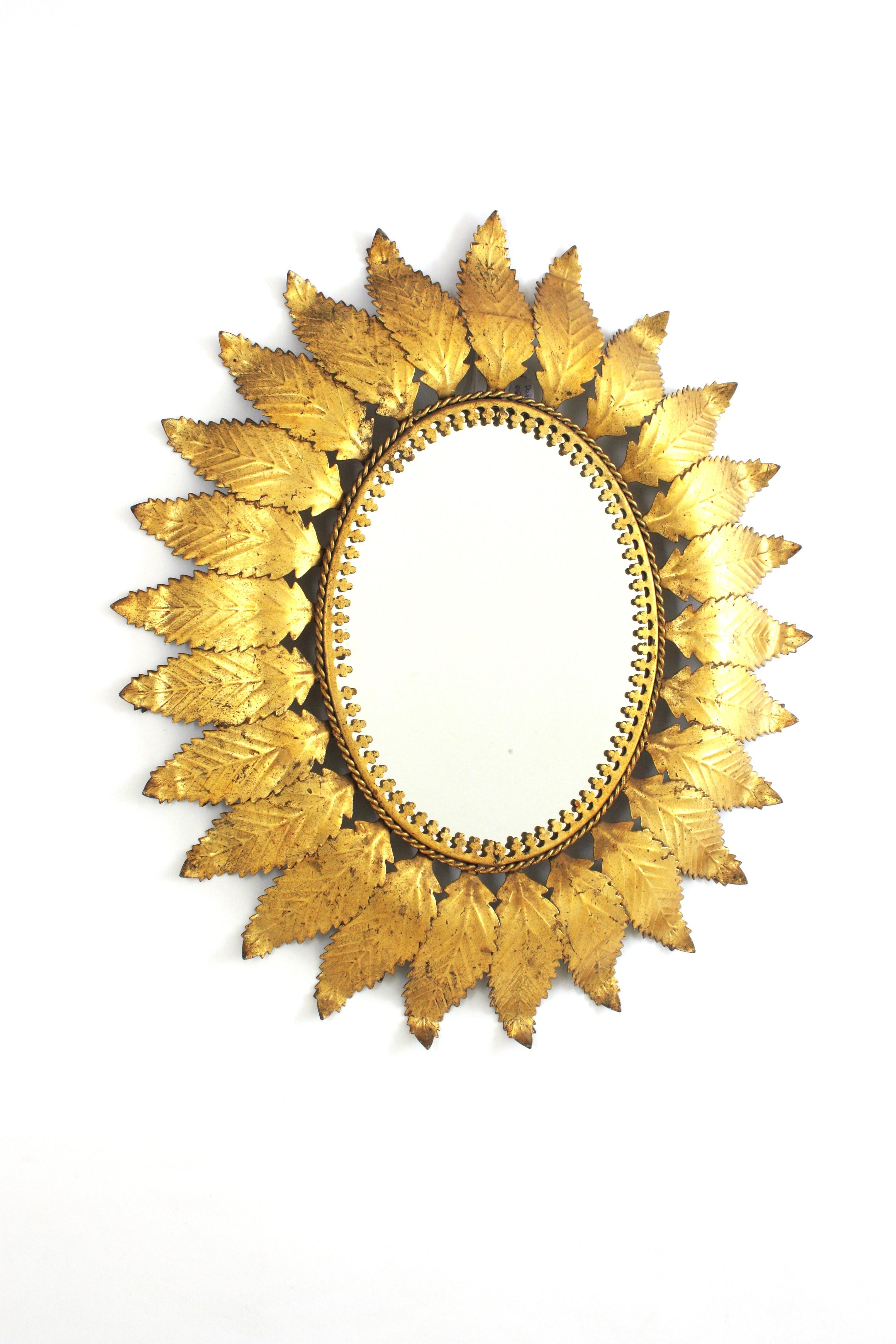 Grande specchio ovale in ferro dorato con cornice a foglie, Spagna, anni 1950-1960.
Un'accattivante specchiera ovale a raggiera incorniciata da grandi foglie smerlate in metallo con finitura dorata.
Questo specchio è in ottime condizioni vintage e