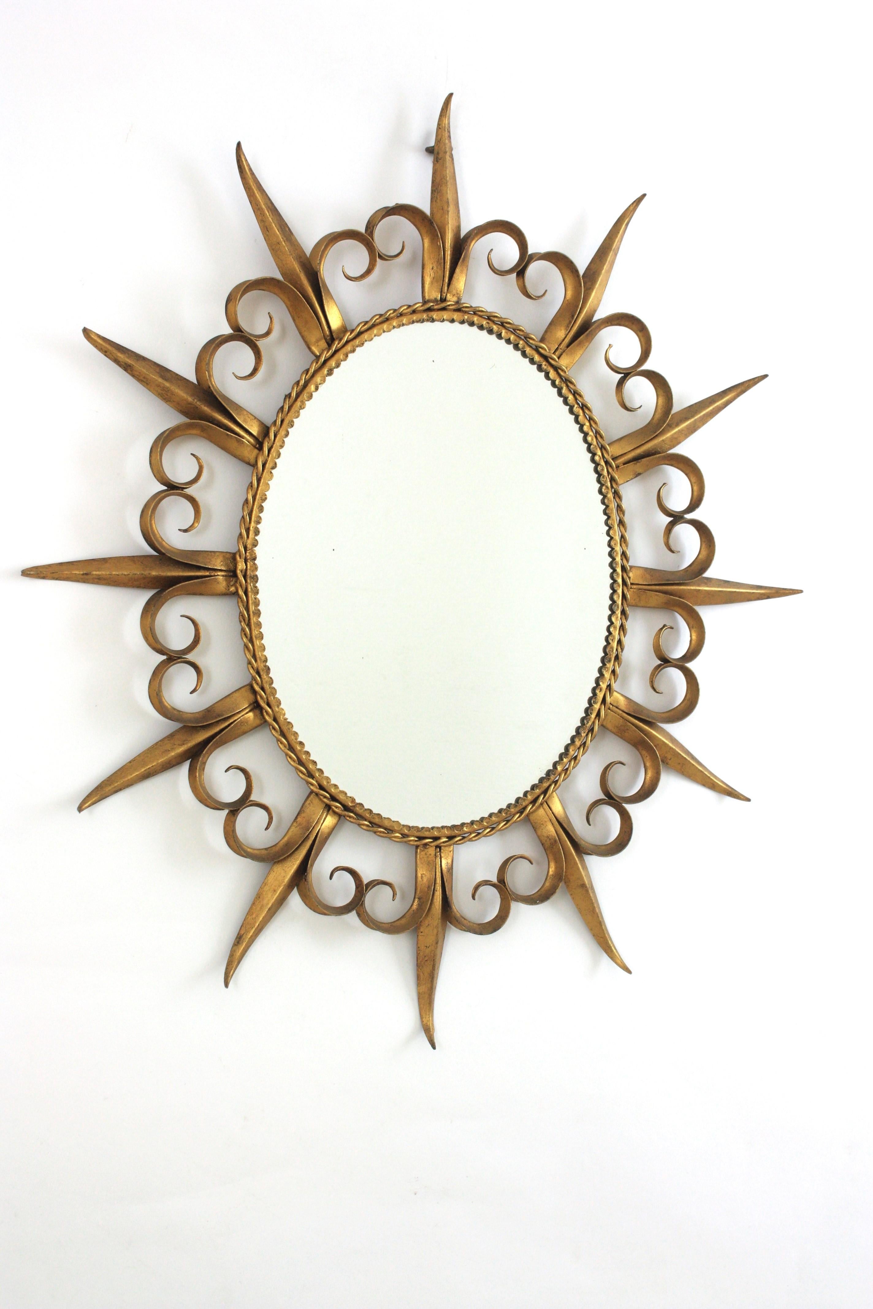 Specchio Sunsburst in metallo dorato con cornice Fleur de Lis o Eyelah, Spagna, anni '50
Elegante specchio a raggiera ovale in ferro battuto dorato della metà del secolo scorso
La cornice presenta un'alternanza di raggi e ciglia e una corda ritorta