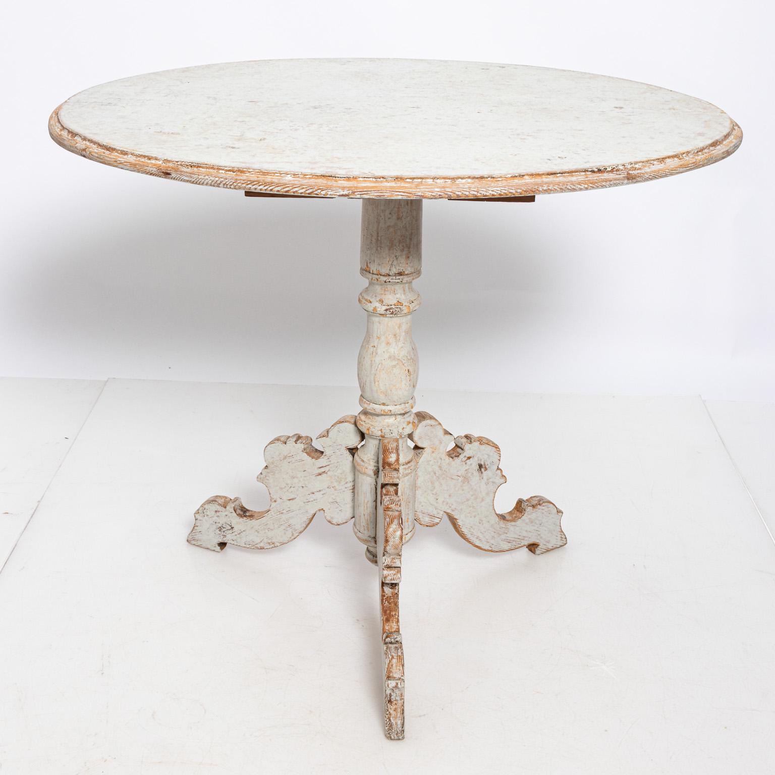 Swedish white painted oval side table with pedestal base and scrolled legs, circa 19th century. The piece features original patina and historic paint. Please note of wear consistent with age.