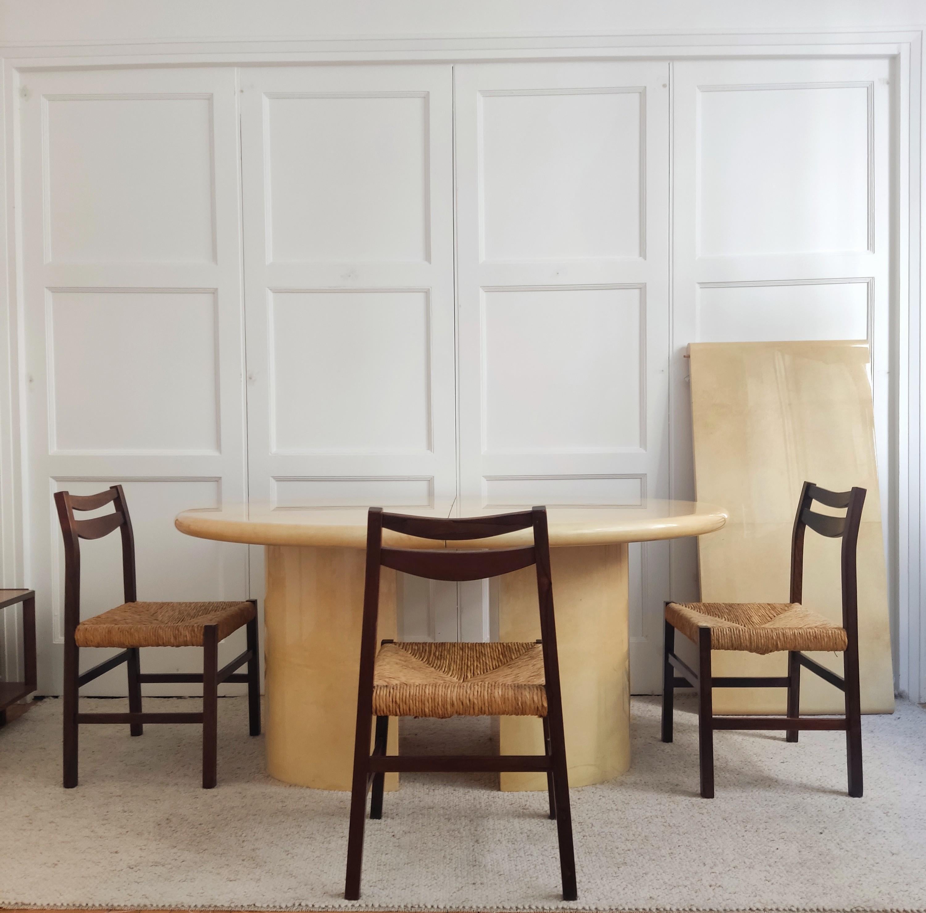 Al estilo de Aldo Tura (1909-1963), mesa ovalada con un grueso tablero moldeado tapizado en cuero barnizado color crema sobre dos patas gemelas macizas con tapas idénticas.

Ligeros signos de uso.

Dimensiones: Alto 73 x Ancho 150 x Fondo 124 cm,