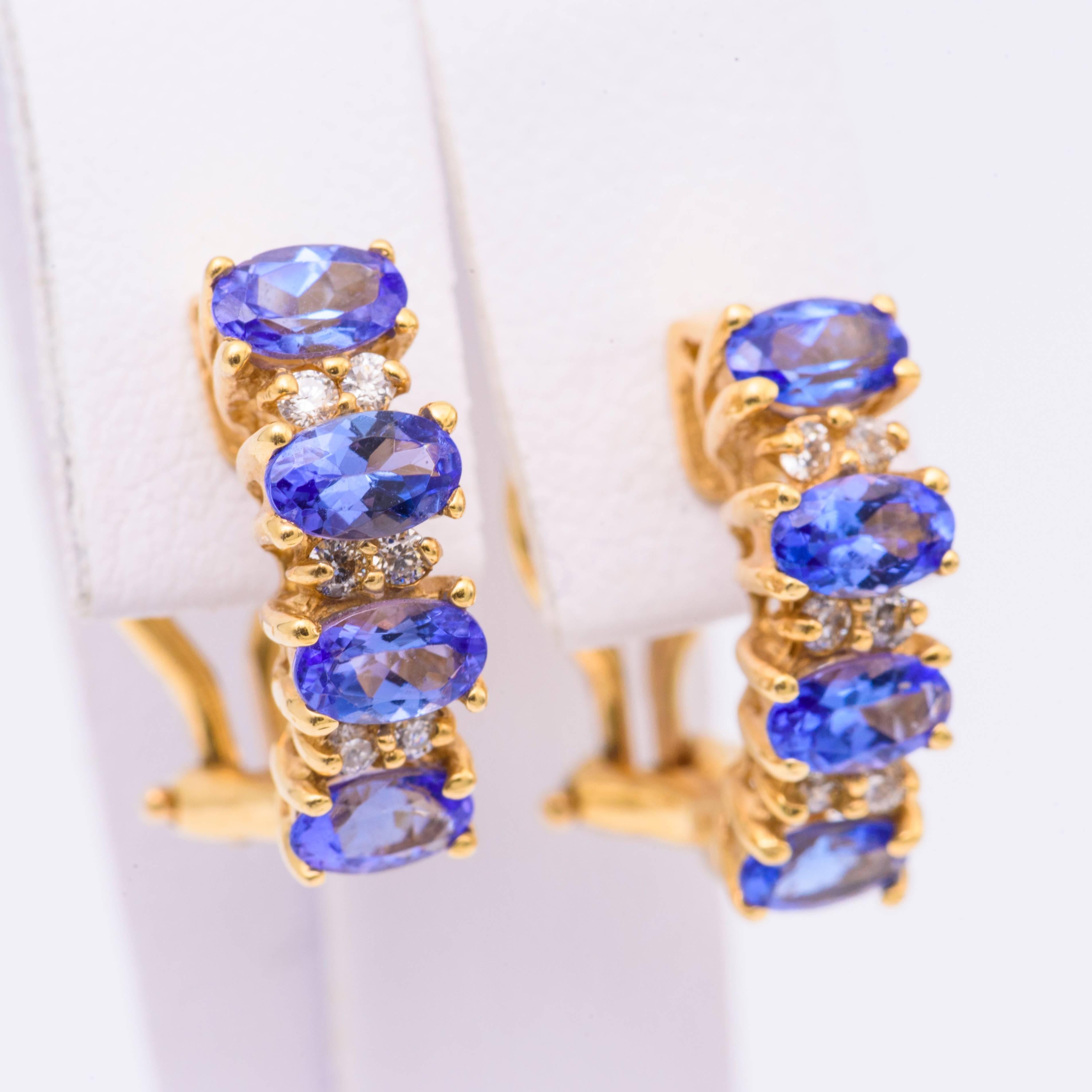 14K Yellow Gold earrings featuring oval cut Tanzanites measuring 5 x 3 mm and weighing 1.90 carats with diamond sections weighing 0.17 carats. Earrings measures 16 x 3 mm.