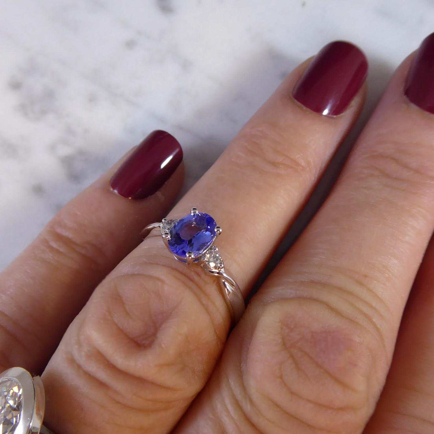 A very pretty three stone ring set with an oval tanzanite measuring 7.0mm x 5.0mm in white four claw setting.  To each side a brilliant cut diamond (total diamond weight 0.10ct) three claw set to twisted shoulders to D shaped, cross-sectioned