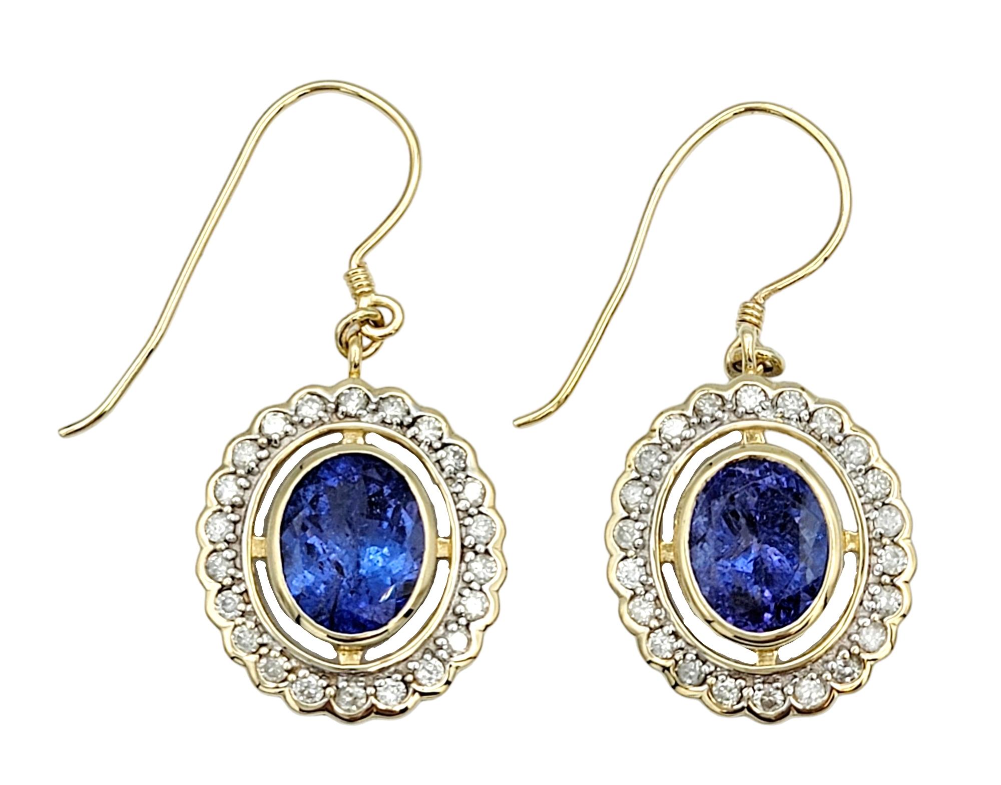These exquisite dangle earrings are a true celebration of beauty and grace, showcasing a design that perfectly balances opulence and sophistication. At their heart, they feature captivating blue oval tanzanite gemstones, their deep and vibrant hue a
