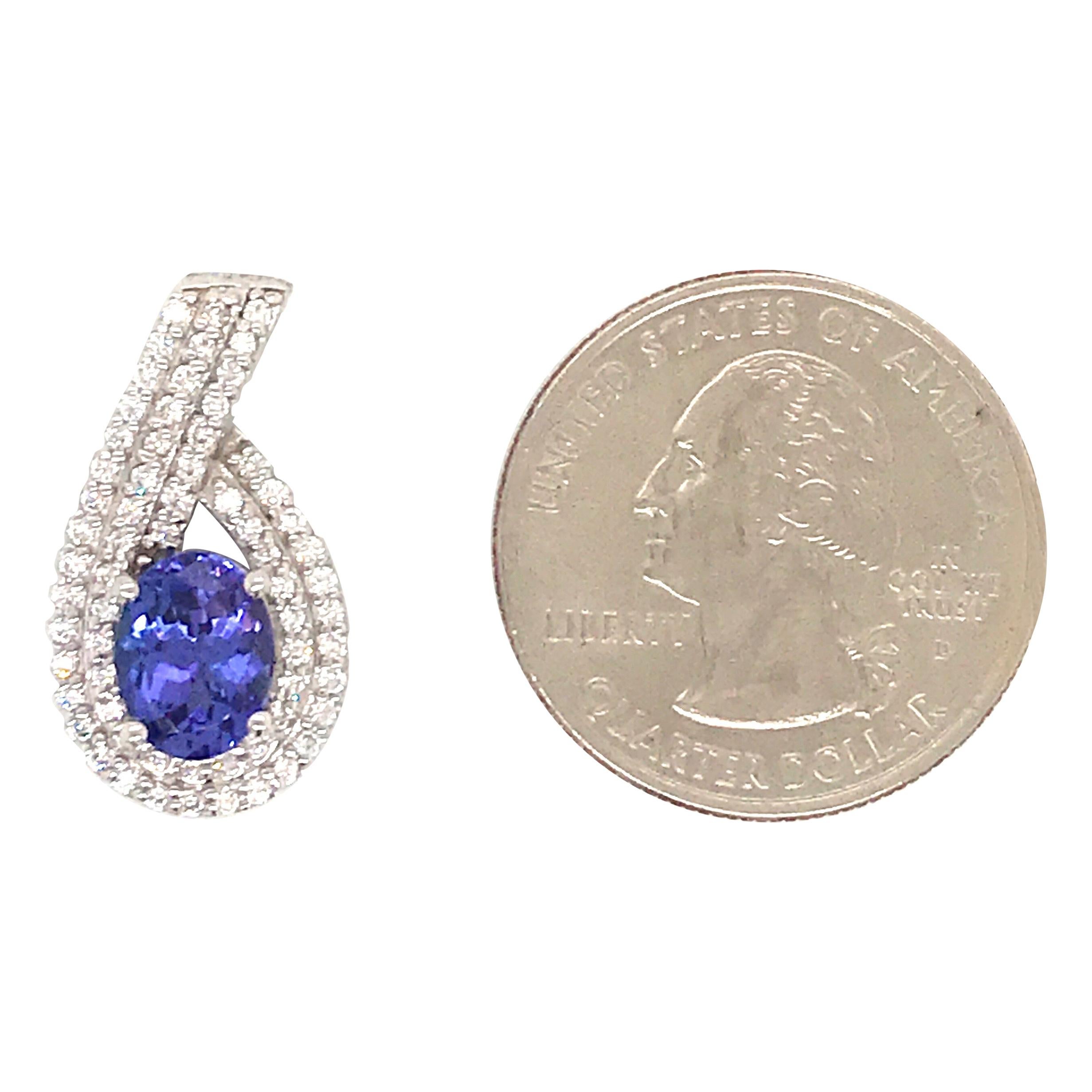 14K White Gold pendant featuring one oval cut tanzanite flanked with round brilliants weighing 0.52 carats. Comes with a 14k white gold chain, 16