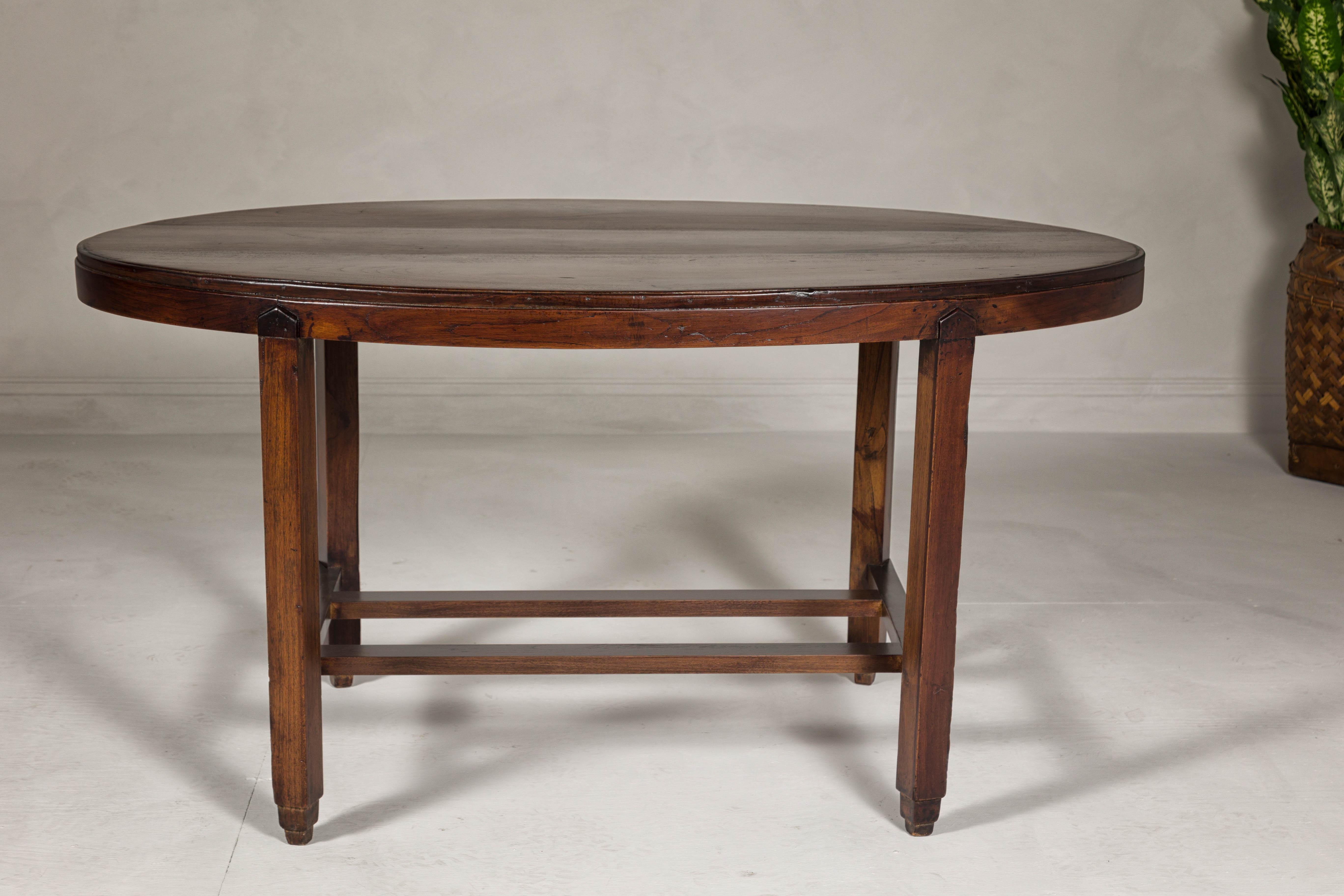 Indonesian Oval Top Center Table with Inverted Stepped Pyramid Feet and Cross Stretcher For Sale