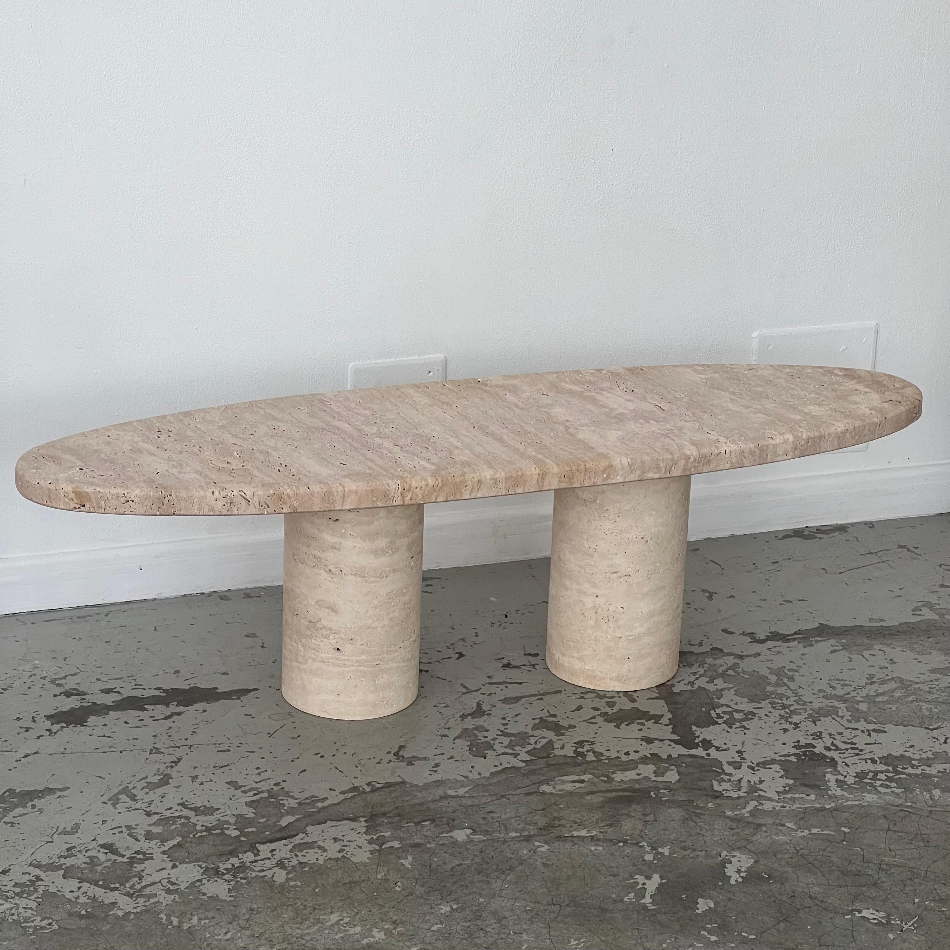 Table in untreated natural travertine. The overall structure is in travertine. The top is oval and rests directly on two solid cylindrical legs. 
In very good condition.