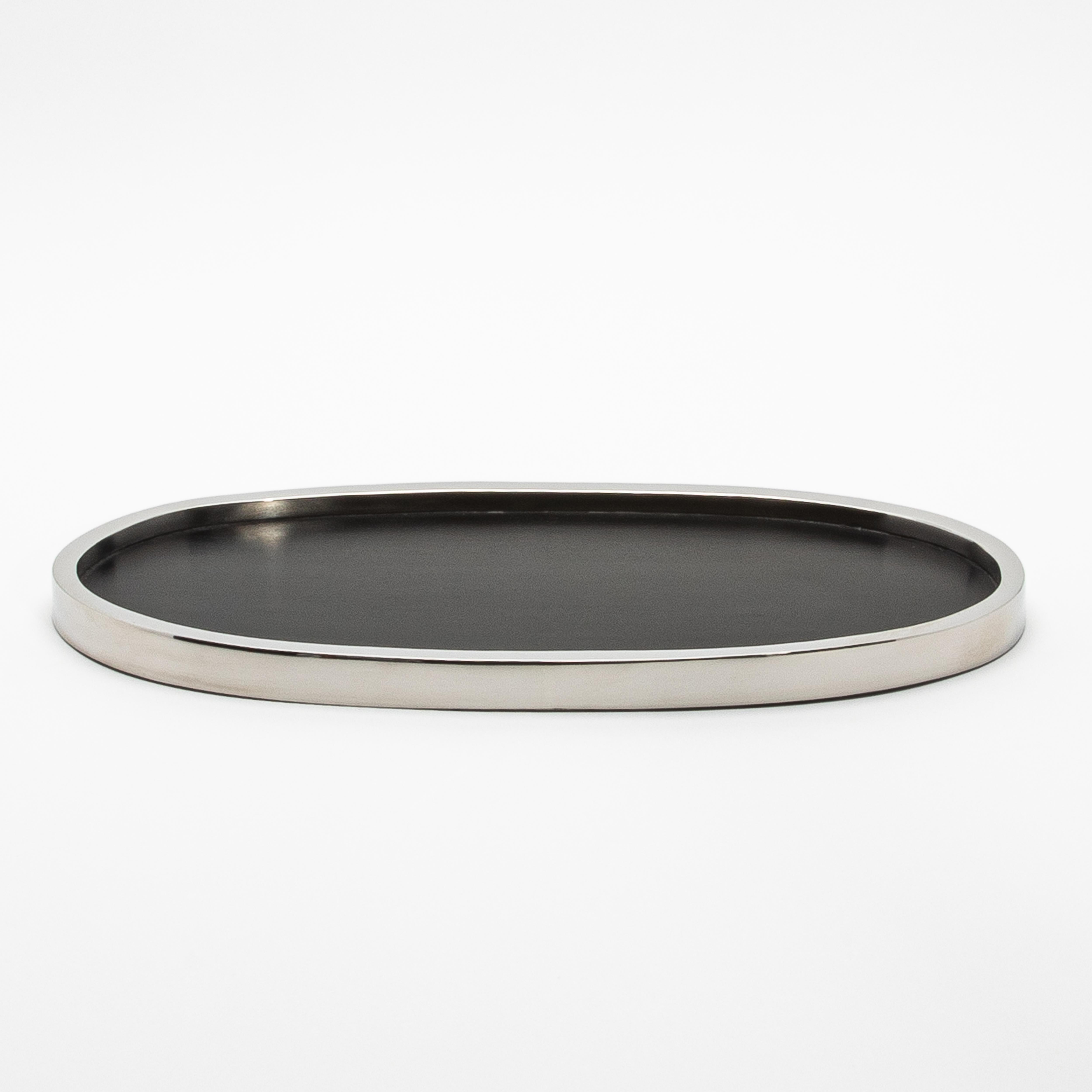 Il vassoio ovale Kifu Paris in quercia nera e acciaio inox lucido è una straordinaria fusione di calore naturale ed eleganza moderna. La superficie del vassoio in rovere nero profondo, con la sua finitura liscia, offre una texture ricca e organica