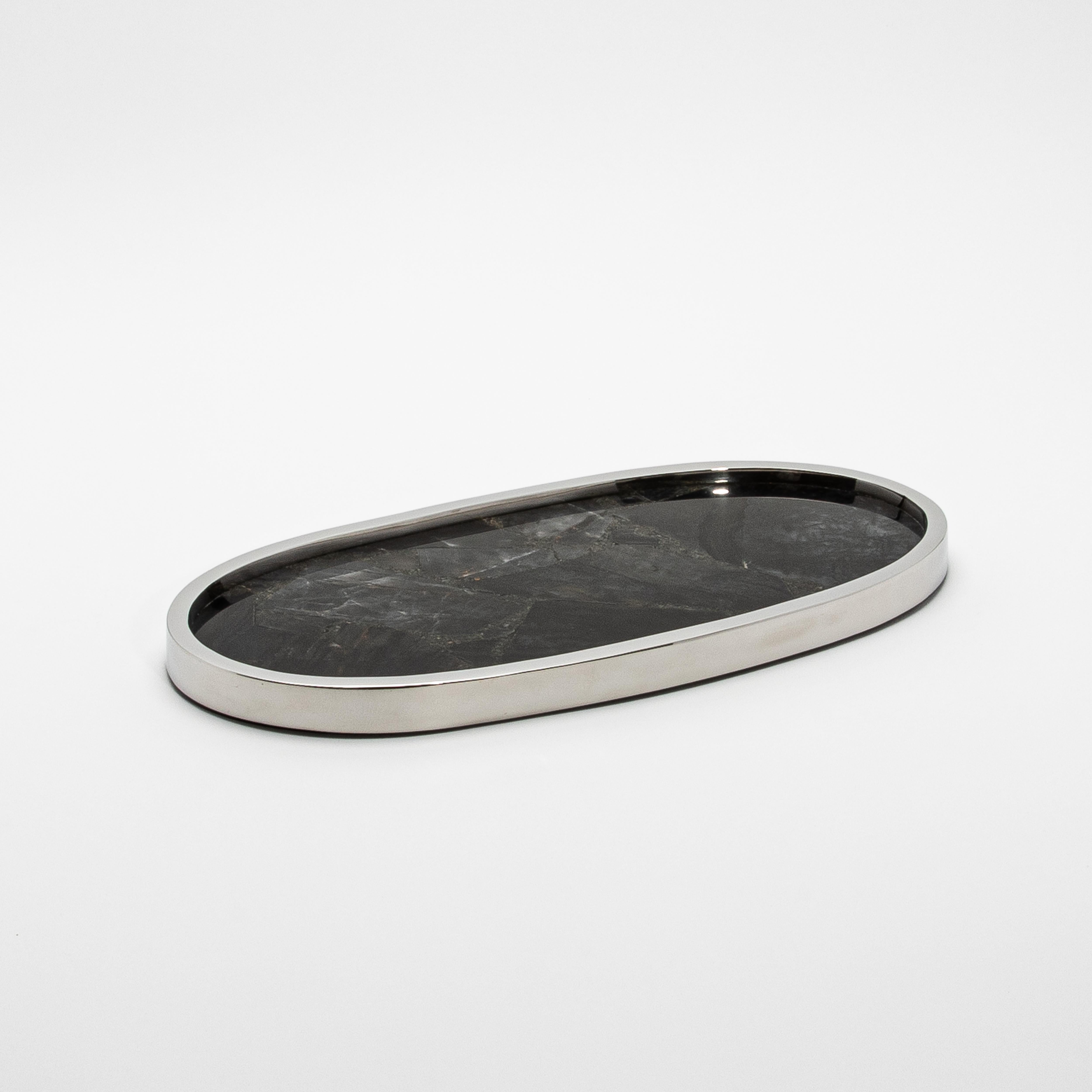 Le plateau ovale Kifu Paris en quartz noir et acier inoxydable poli est une vitrine étonnante de la beauté naturelle et de l'élégance moderne. La surface en quartz noir, fabriquée à la main, présente des veines complexes et une finition profonde et