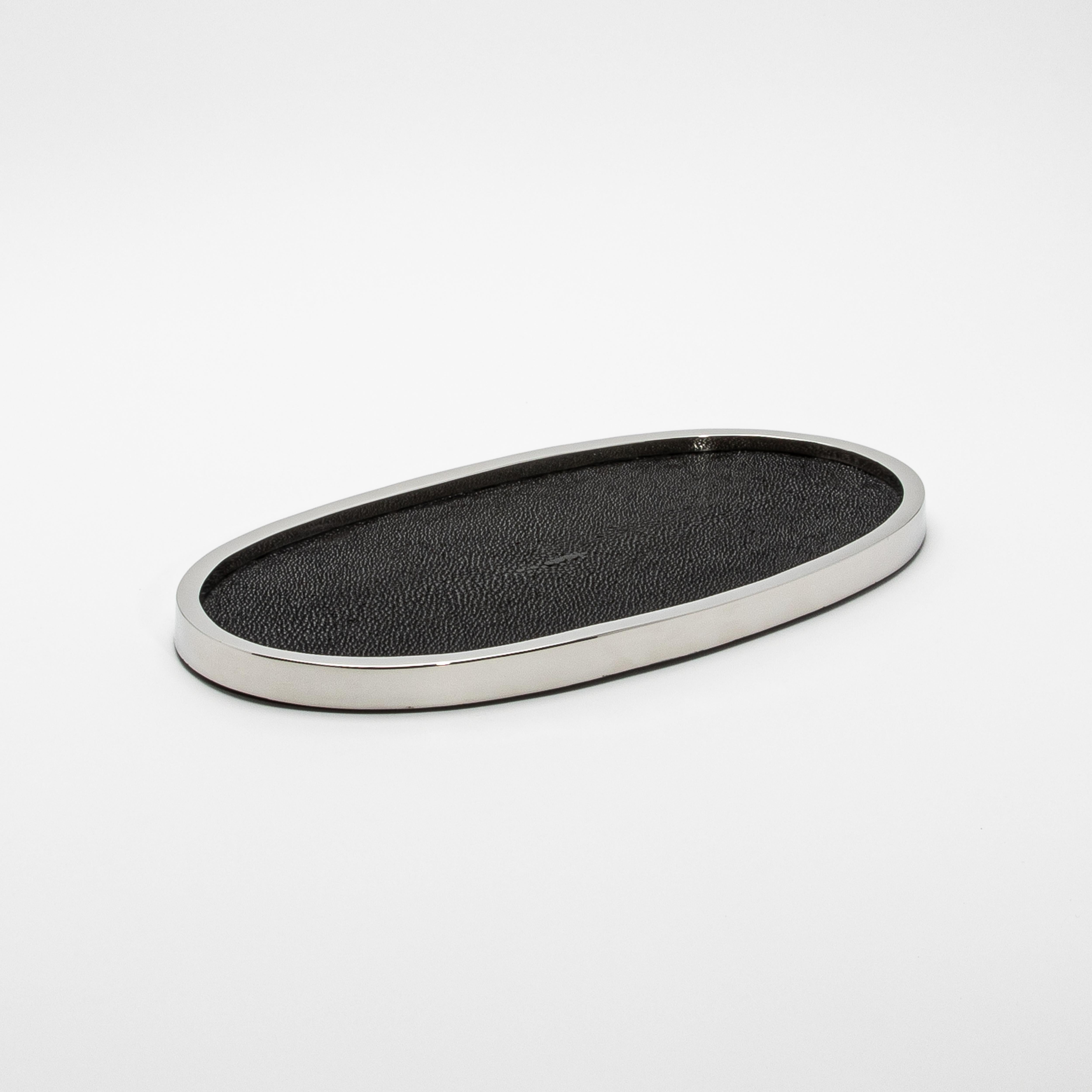 Le plateau ovale Kifu Paris en galuchat noir et acier inoxydable poli présente un équilibre saisissant entre une texture audacieuse et une sophistication épurée. La riche surface en galuchat noir, réalisée à la main, ajoute un élément tactile et