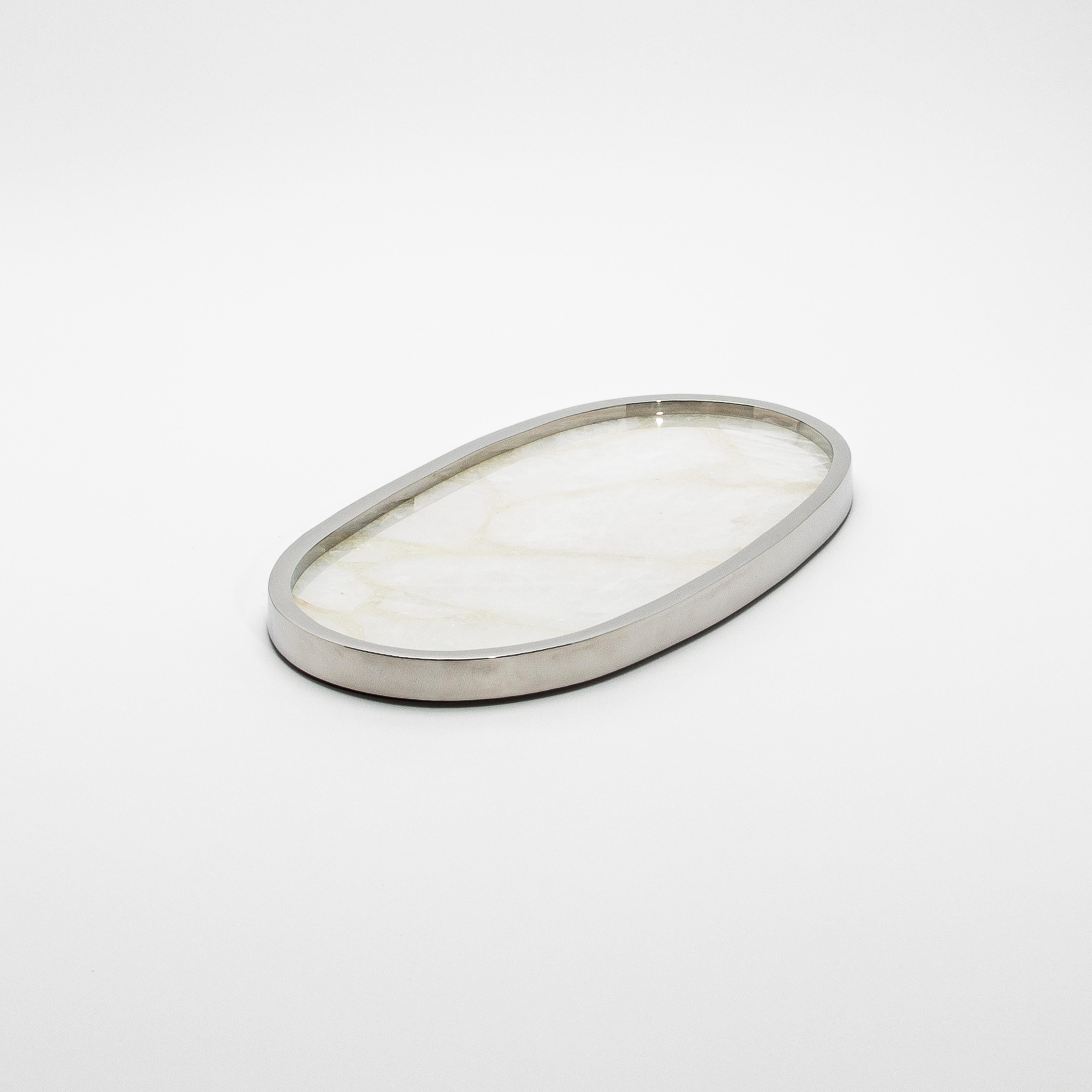 Le plateau ovale Kifu Paris en quartz blanc et acier inoxydable poli apporte un air de sophistication raffinée à tout environnement. La surface en quartz blanc, fabriquée à la main, présente une élégance lisse et naturelle, avec des veines douces