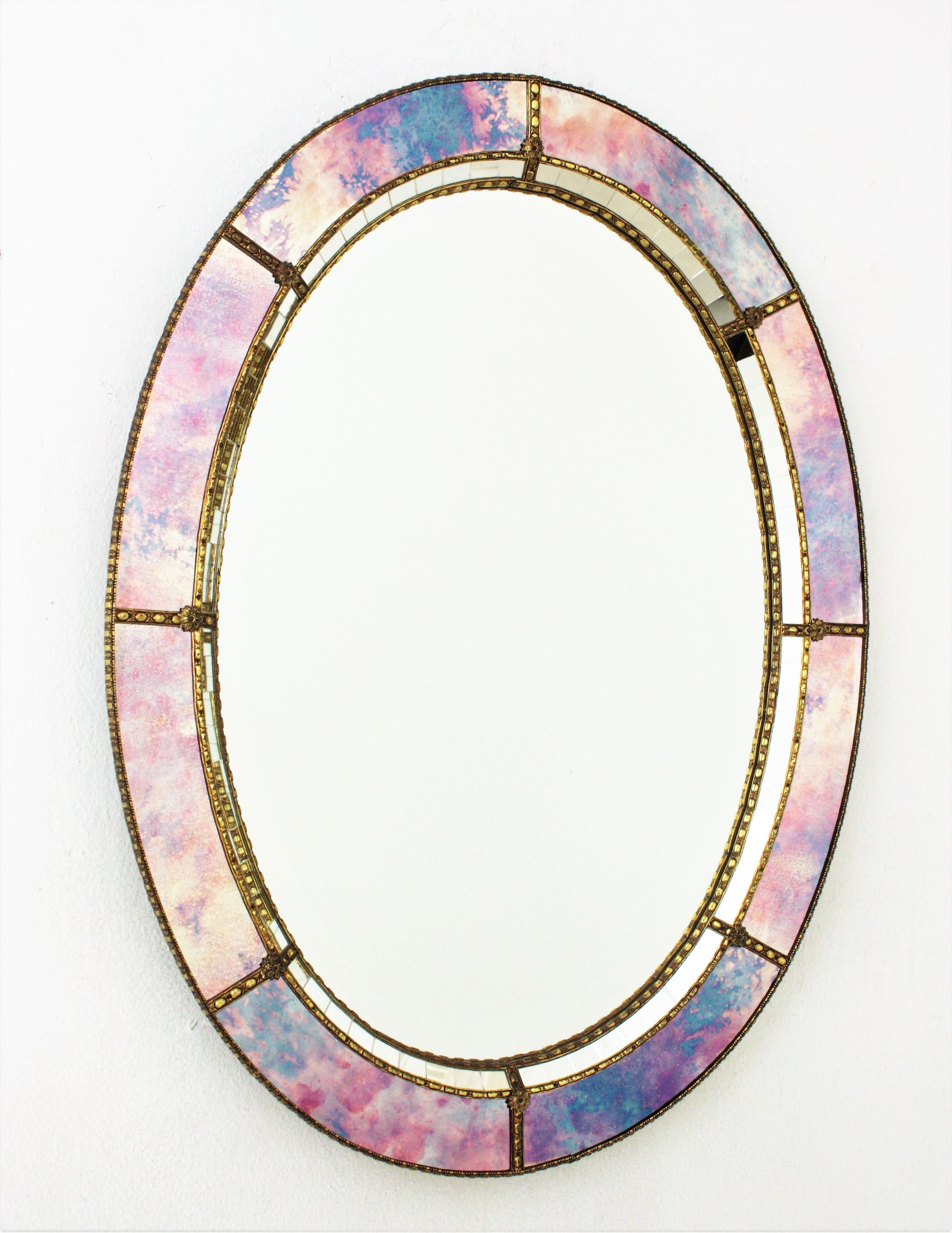 Elegant Venetian style Hollywood Regency oval mirror with iridiscent and mirror glass panels. Spain, 1960s
This glamorous mirror featuring a double layered mirror frame made of brass. Oval form with a frame that has two layers of decorative paneled