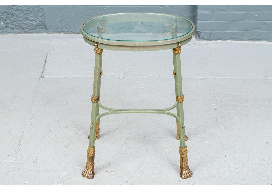 An oval verdigris patinated iron table with inset glass top, conjoined C-form stretchers and resting on four brass decorated legs with brass paw feet.
Dimensions: 18 1/2