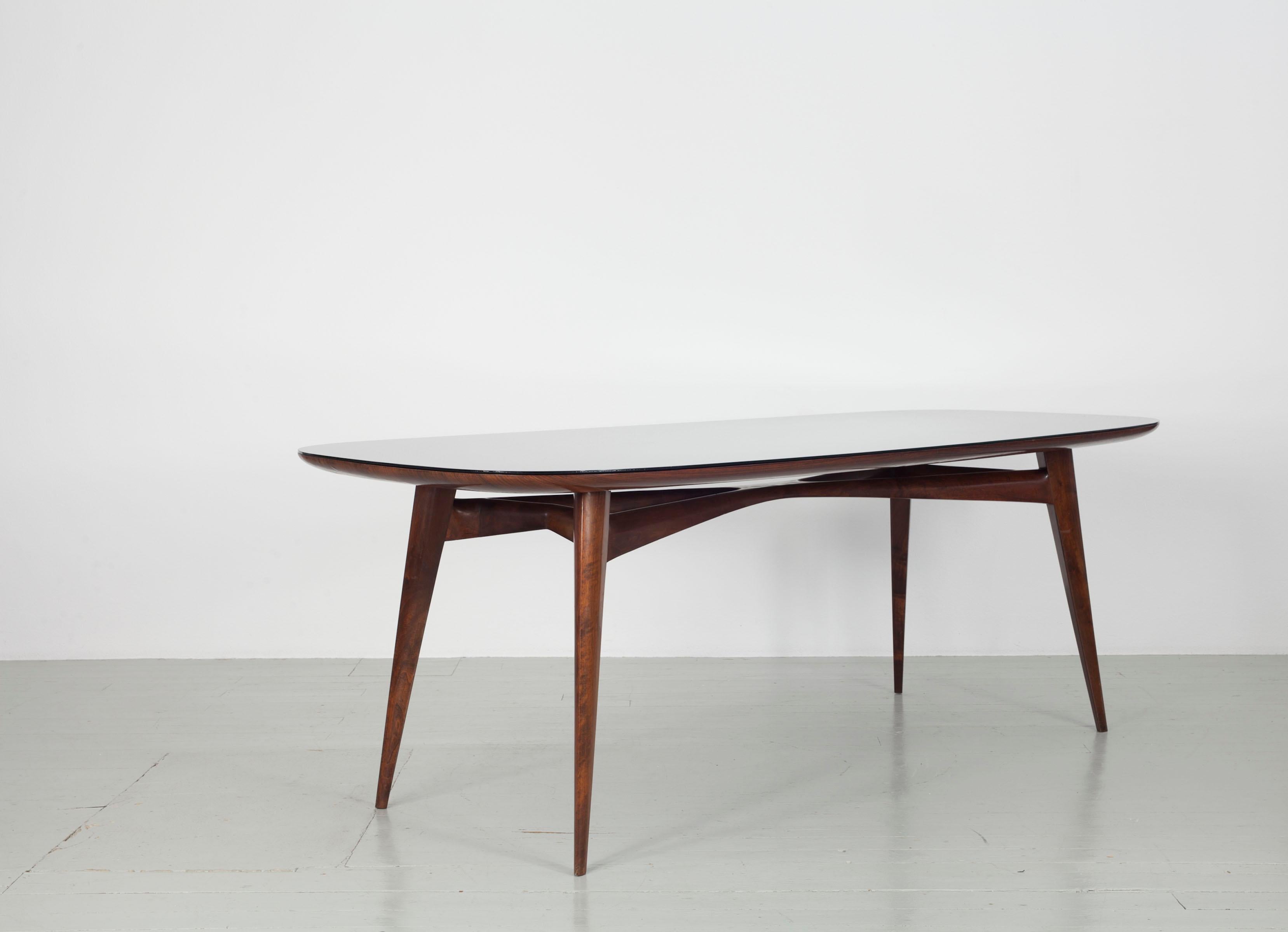 This elegant dining table was designed by Vittorio Dassi in Italy in the 1950s. Both the table legs and the tabletop are made of lacquered rosewood. There is a black coloured glass overlay on the table top. The thin table legs and the extraordinary