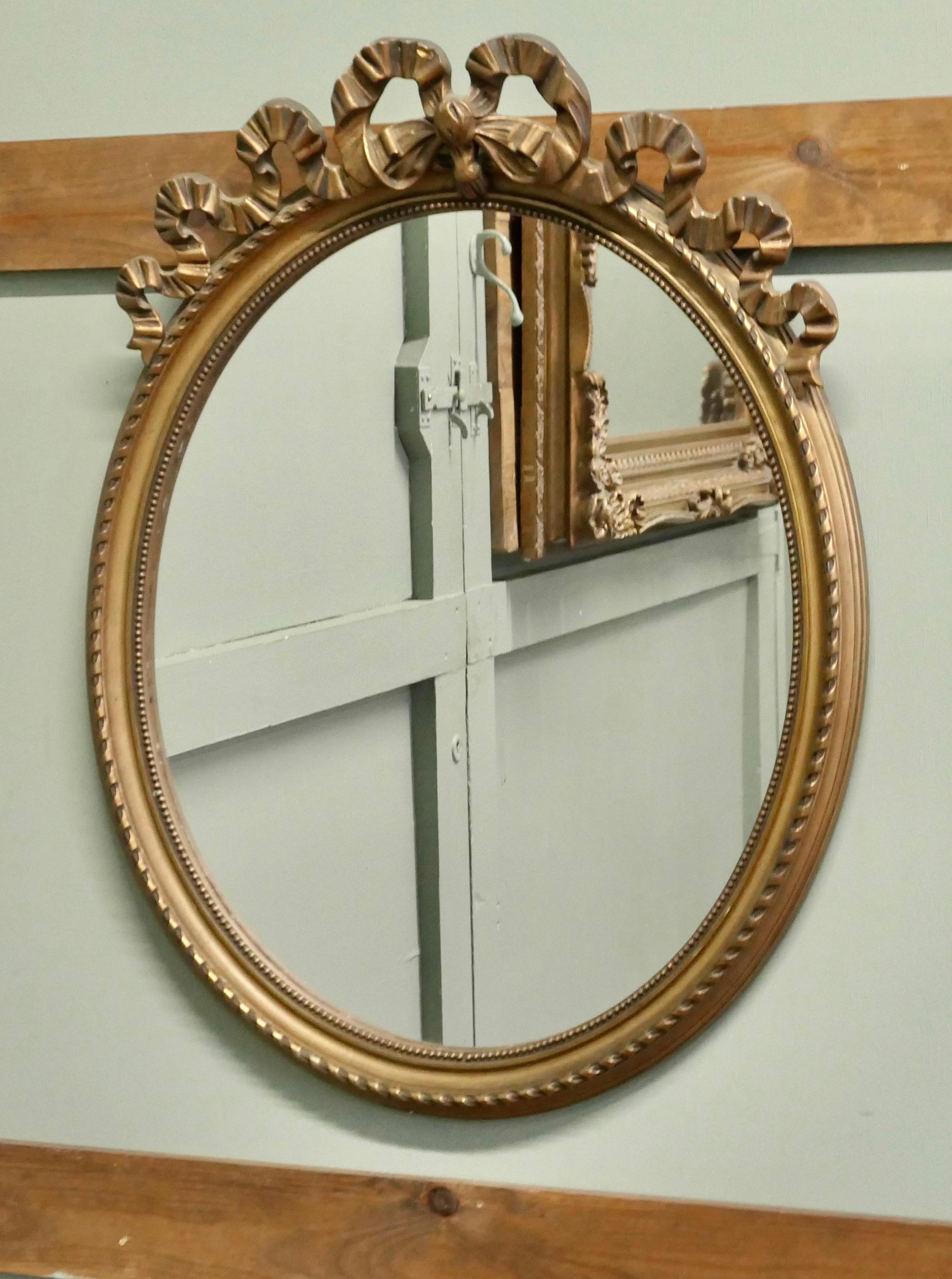 Art Déco Specchio ovale da parete dorato e decorato con nastri  Un pezzo incantevole in vendita