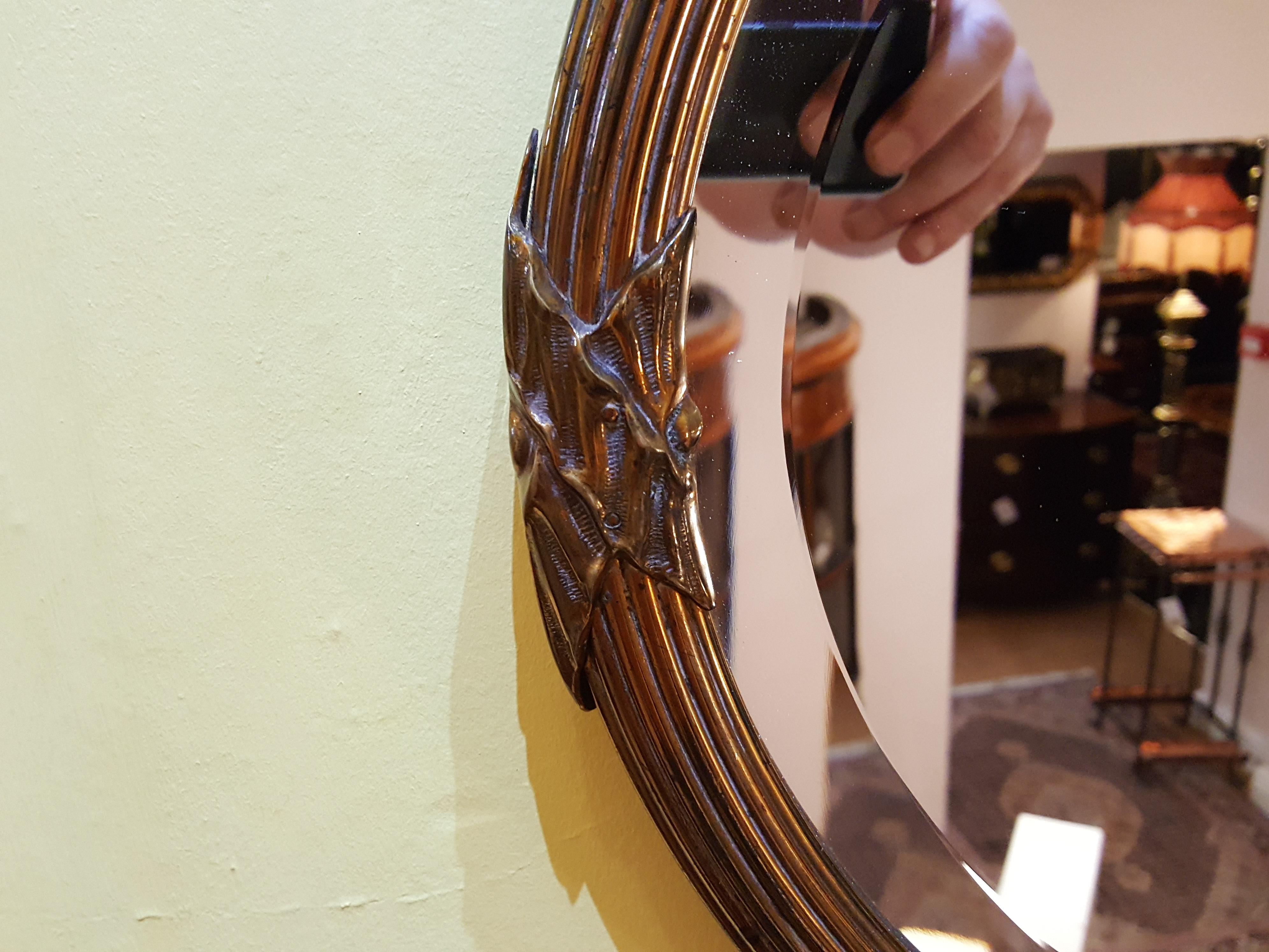 Oval wall mirror with a bevelled edge and gilt ribbed metal rim. Measures: 28