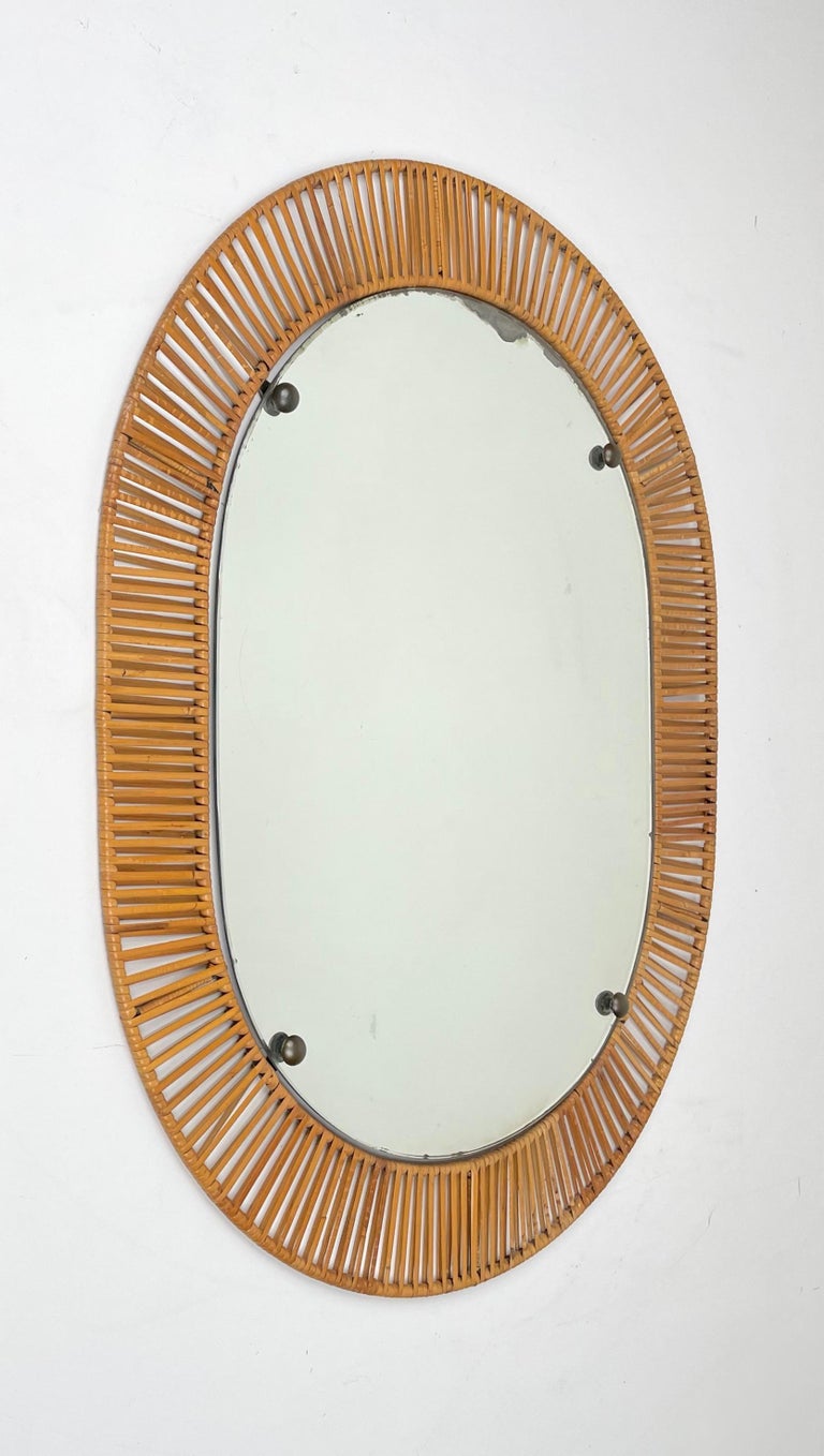 Oval wall mirror featuring a rattan on iron frame made in Italy in the 1960s.