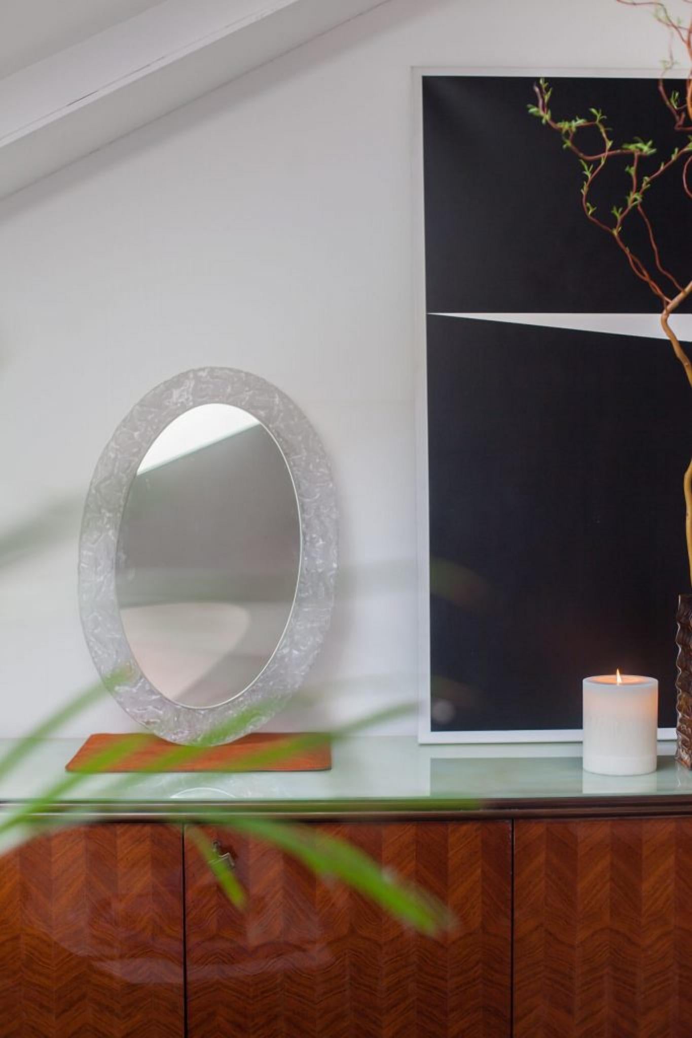 Oval wall mirror, with frame in transparent textured Lucite.

This wall mounted Lucite mirror is truly a statement piece that adds both visual interest and functionality to any room, showcasing the creativity and quality craftsmanship of the