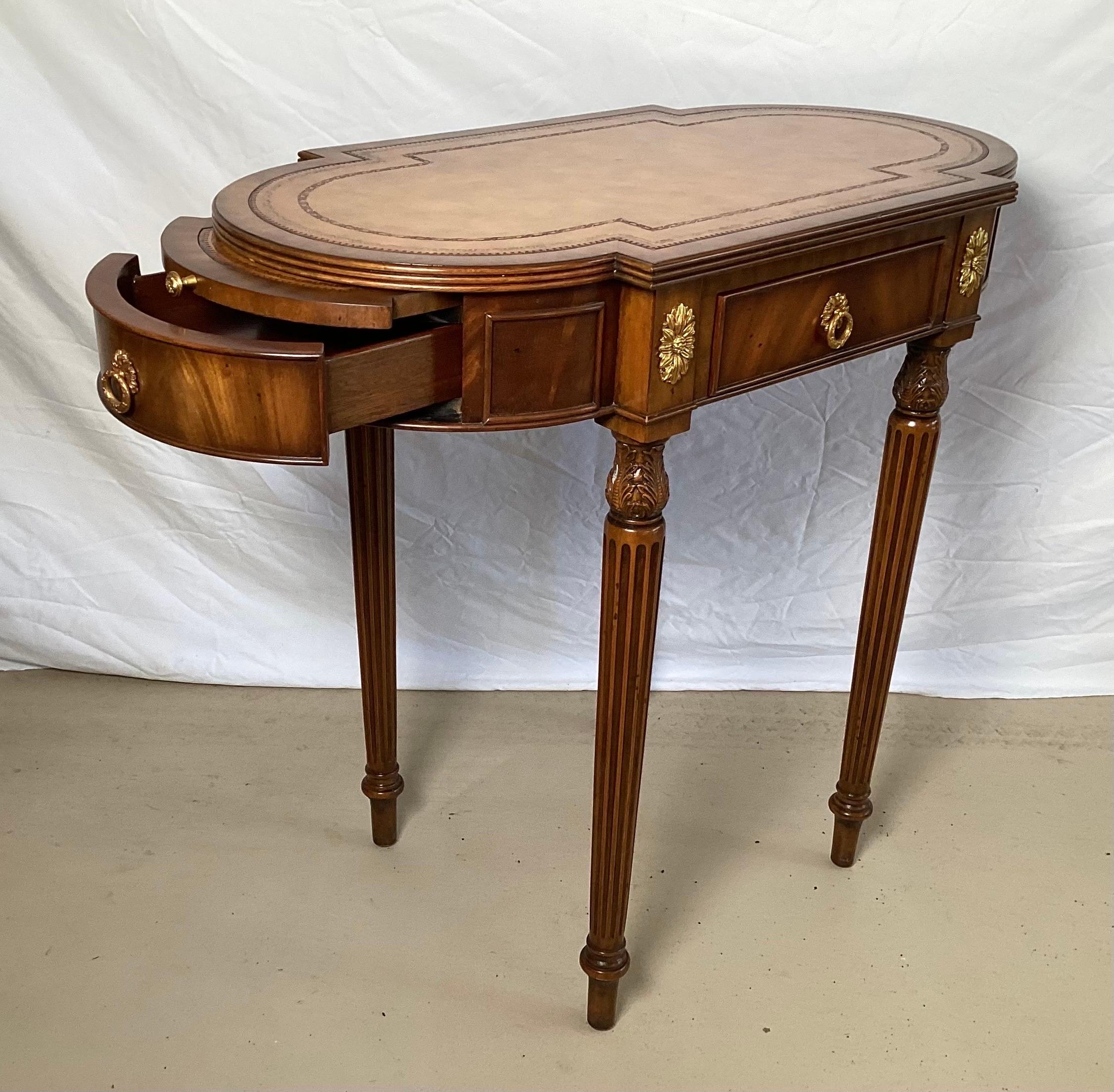 Graceful oval burl walnut and leather topped accent work table by Maitland Smith. The warm walnut and mahogany with a tan tooled leather top with ormolu mounts. The table with three drawers, one on each side and one at the from with two pull out