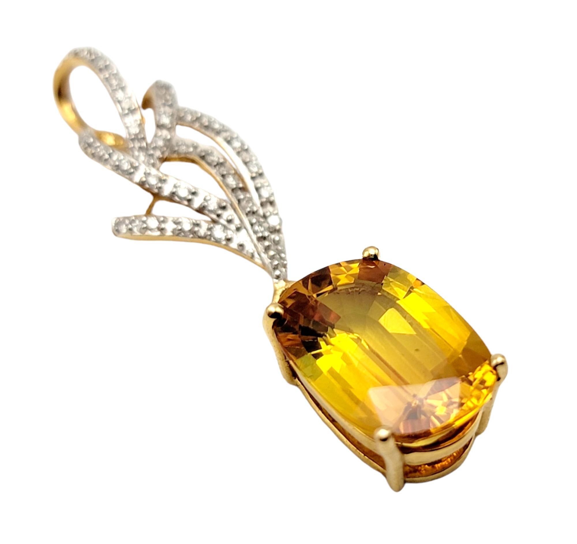 Elegant vertical pendant featuring a large yellow sapphire and sparkling pave diamonds. The stunning 4 prong set oval mixed cut yellow sapphire pops against the warm yellow gold setting, while the twisted 'flame' of natural white diamonds really