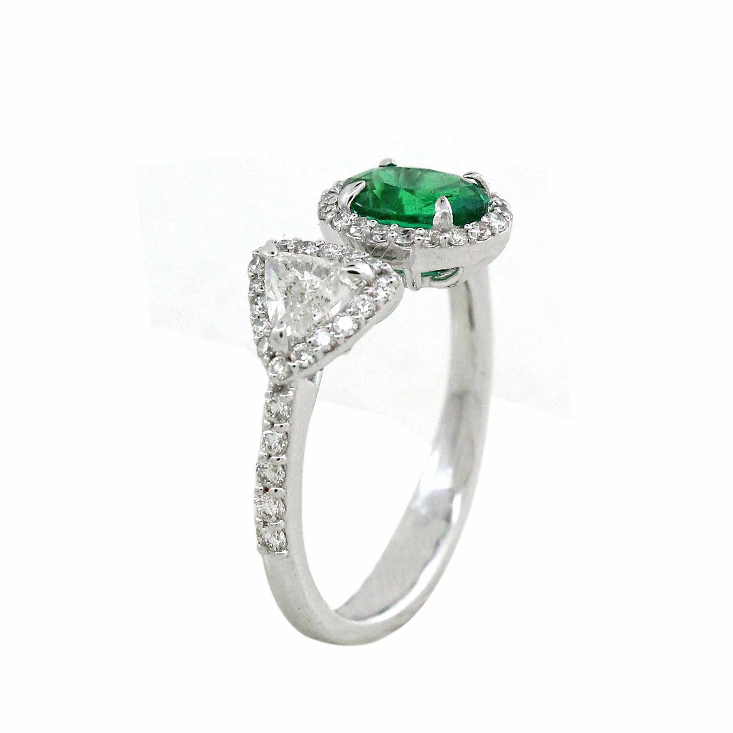 Stunning masterpiece, a resplendent Oval Zambian emerald weighing 0.72 carats sits majestically between halo of 46 brilliant cut white diamonds totaling to 0.31 carats. This vibrant green gemstone symbolizes eternal love and growth. Fancy Trillion