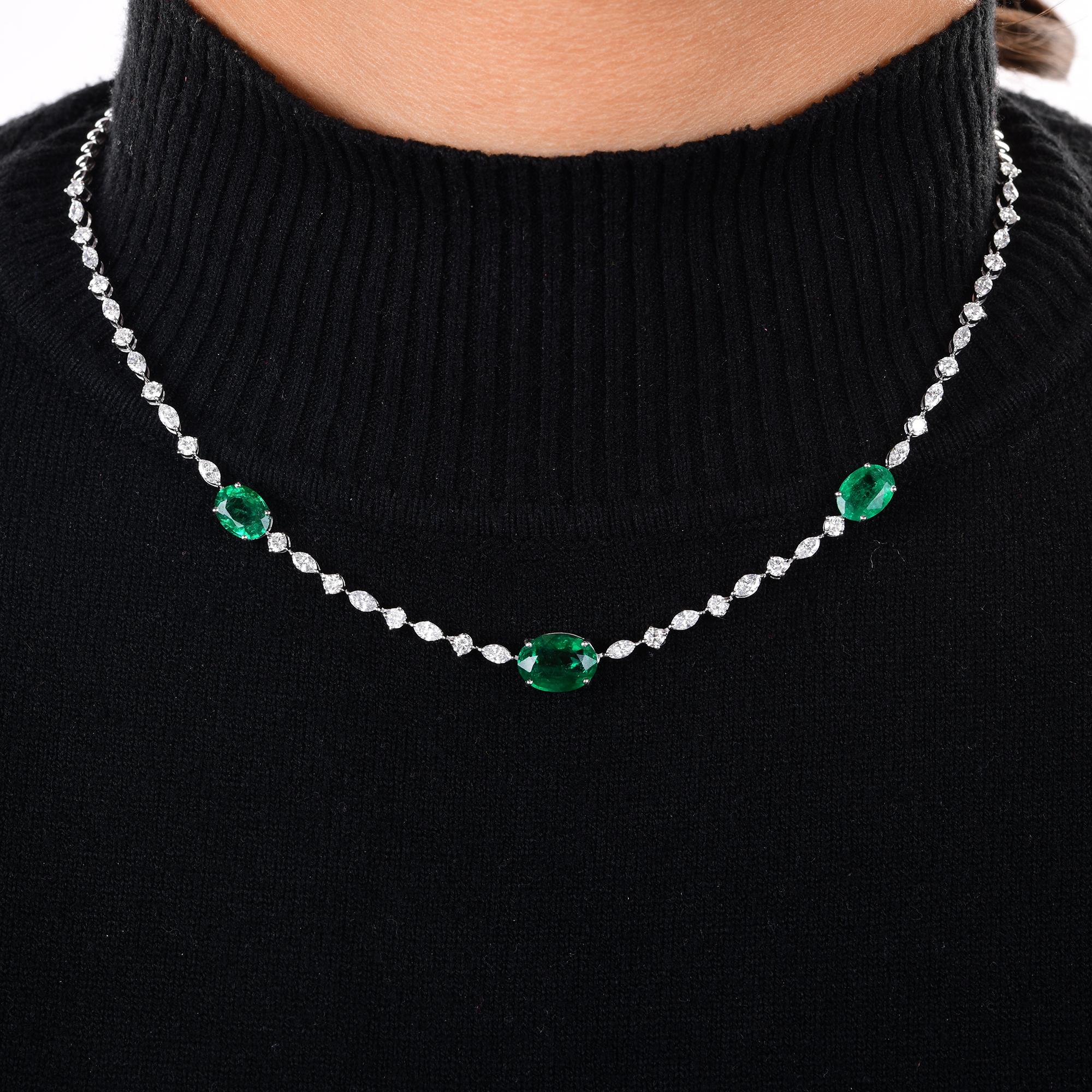 Ce collier �à chaîne de diamants en or blanc 14 carats, composé d'émeraudes ovales de Zambie, présente un design gracieux et raffiné. Sur la longueur de la chaîne, trois émeraudes de taille ovale occupent le devant de la scène. Entre les émeraudes,