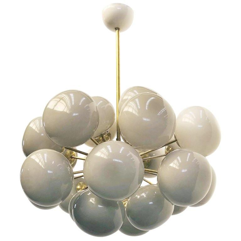 Lampadario italiano di forma ovale con paralumi in vetro di Murano color crema montati su una struttura in ottone / disegnato da Fabio Bergomi per FABIO LTD / Made in Italy
24 luci / tipo E12 o E14 / max 40W ciascuna
Misure: Diametro 36 pollici,