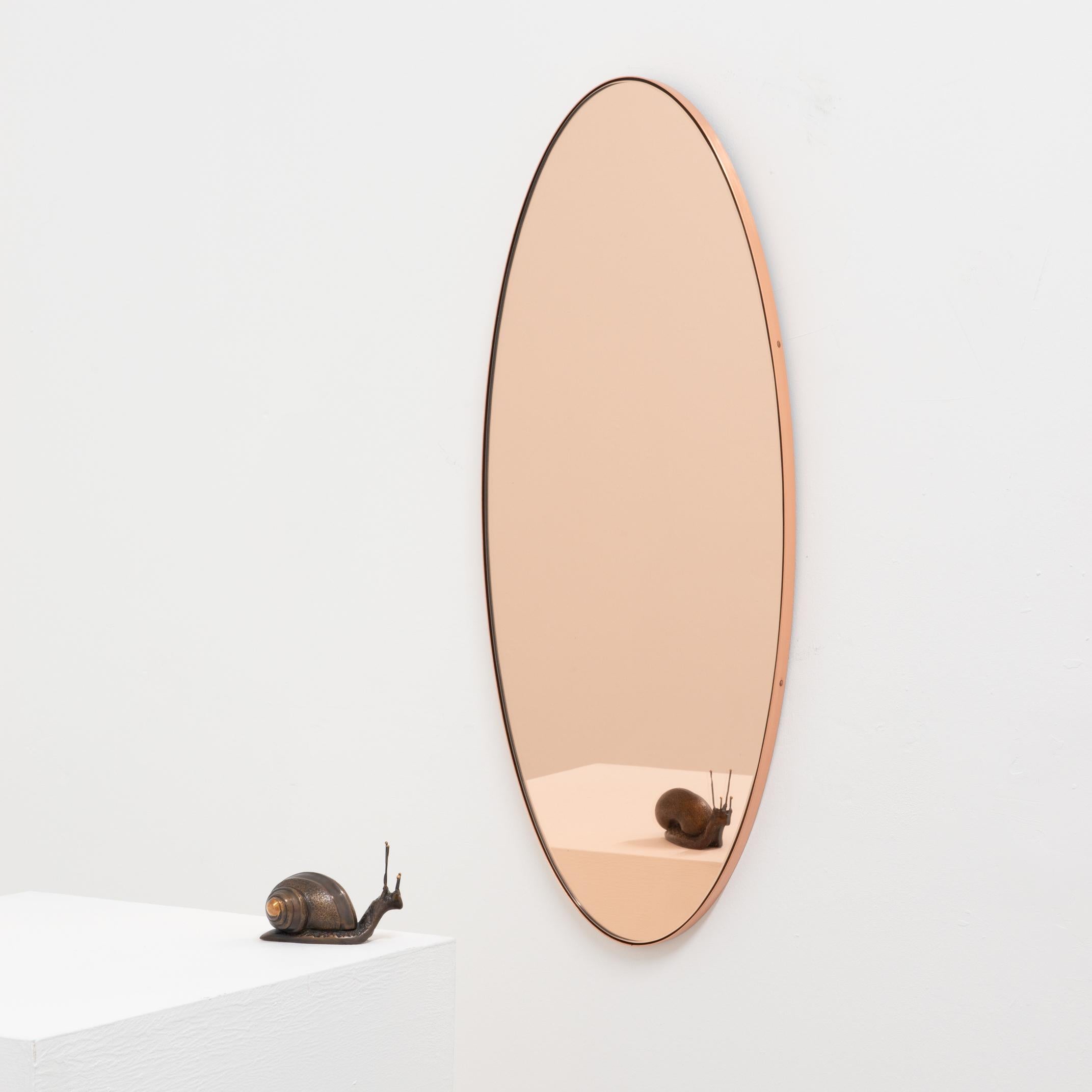 Contemporary oval shaped rose gold / peach mirror with an elegant copper frame. Designed and handcrafted in London, UK. Supplied fully fitted with a specialist hanging system for an easy installation.

The pictures show a small size, measuring