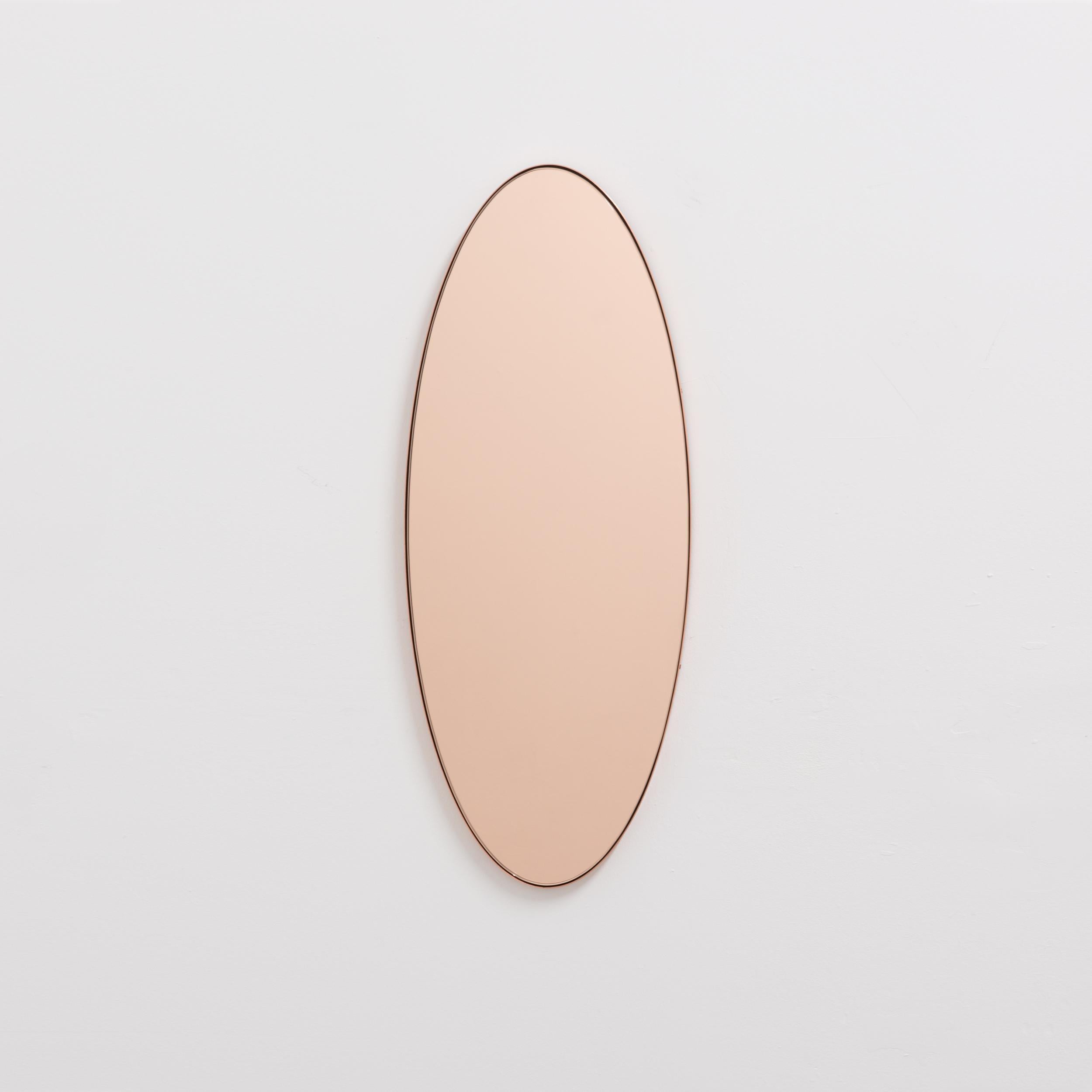 Miroir contemporain de forme ovale en or rose/pêche avec un élégant cadre en cuivre. Conçu et fabriqué à la main à Londres, au Royaume-Uni. Livré entièrement équipé avec un système d'accrochage spécialisé pour une installation facile.

Les miroirs