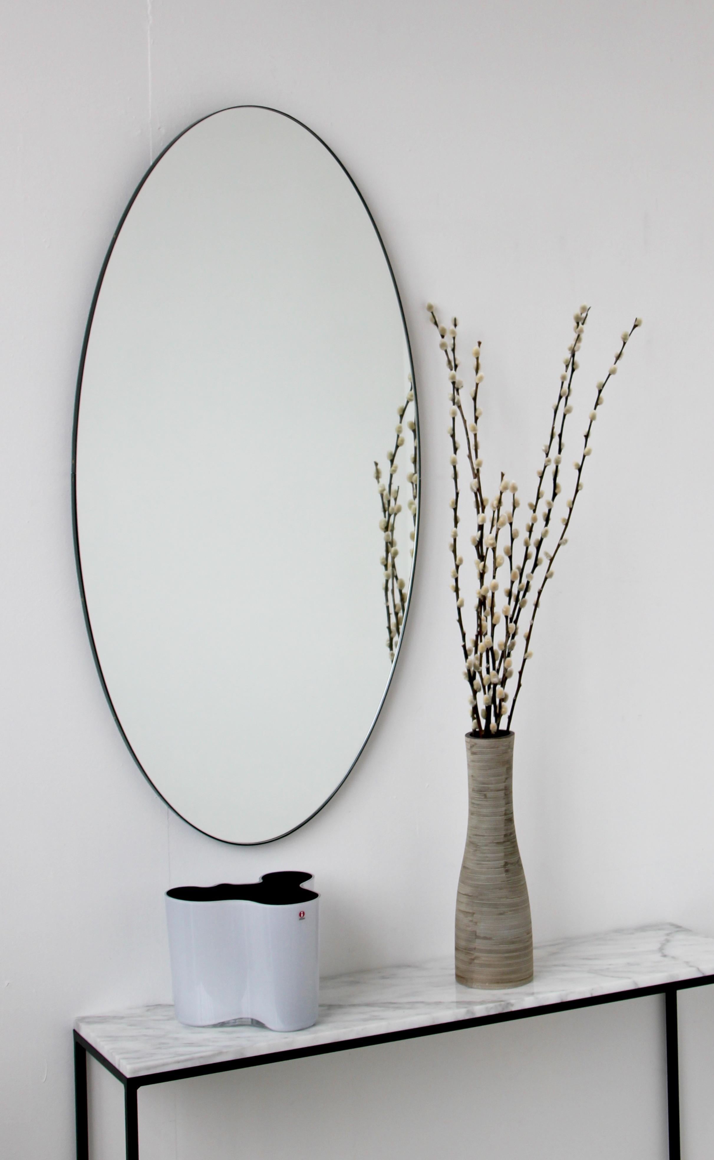 Delightful handcrafted silver oval mirror with a black frame. Designed and made in London, UK.

Measures: w 48cm x h 97cm x d 1.8cm /  w 18.9'' x h 38.2'' x d 0.7''

We supply in custom size, mirror tint or frame finish, and offer beveling as an