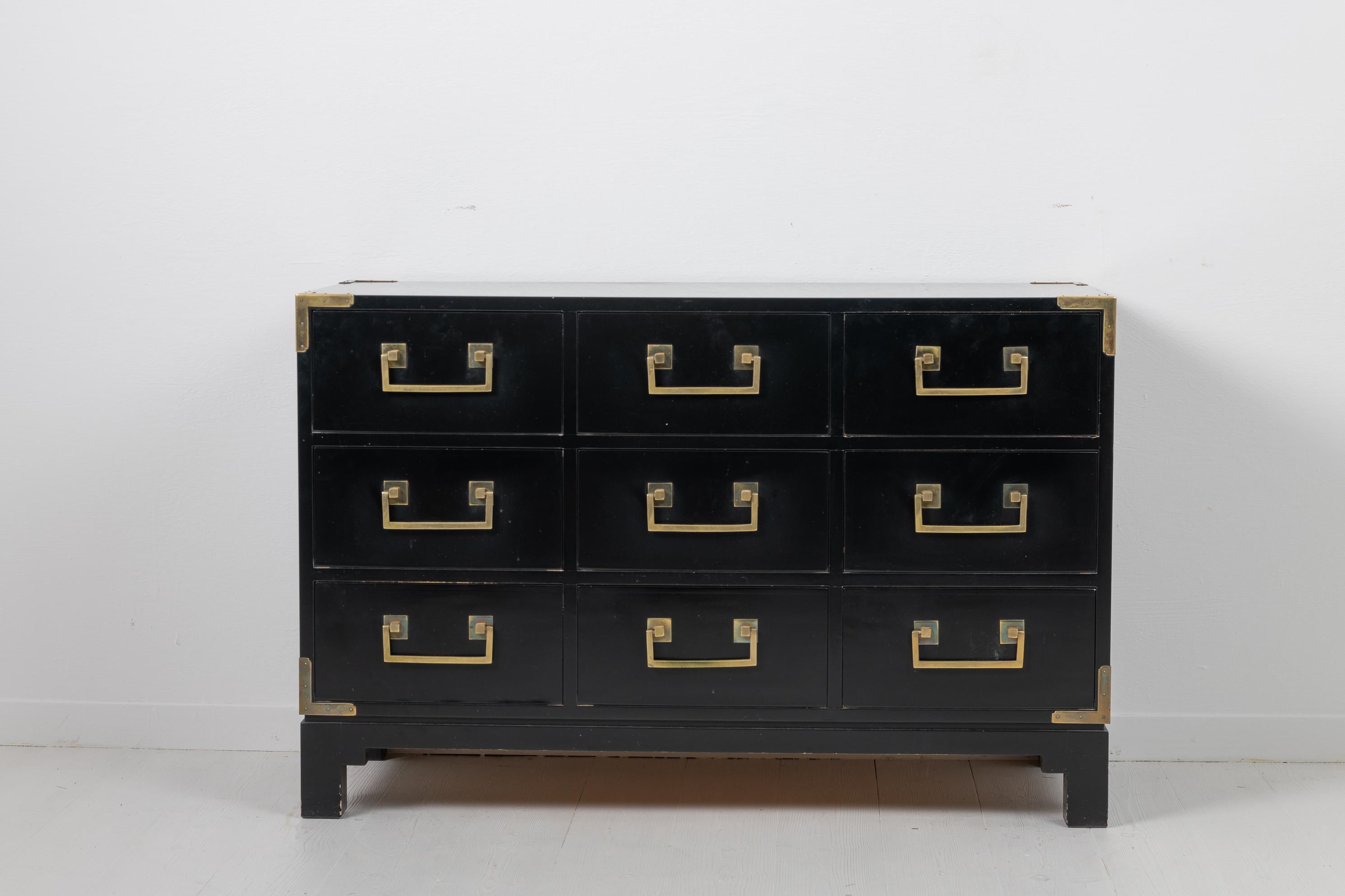 Black Scandinavian Modern chest of drawers by Ove Feuk for Nordiska Kompaniet. The chest is of the model 013 and from the 1960s to 1970s. Marked on the inside. The chest has 9 drawers, each with a statement brass handle, as well as corner plates in