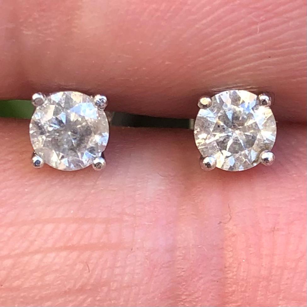Classic over 1/2 carat solitaire diamond stud earrings in 14k white gold. Pair of natural earth-mined enhanced round brilliant diamonds weighing approx. 0.60 carat are prong set in these 14K gold basket studs.

Diamond stud earrings come with solid