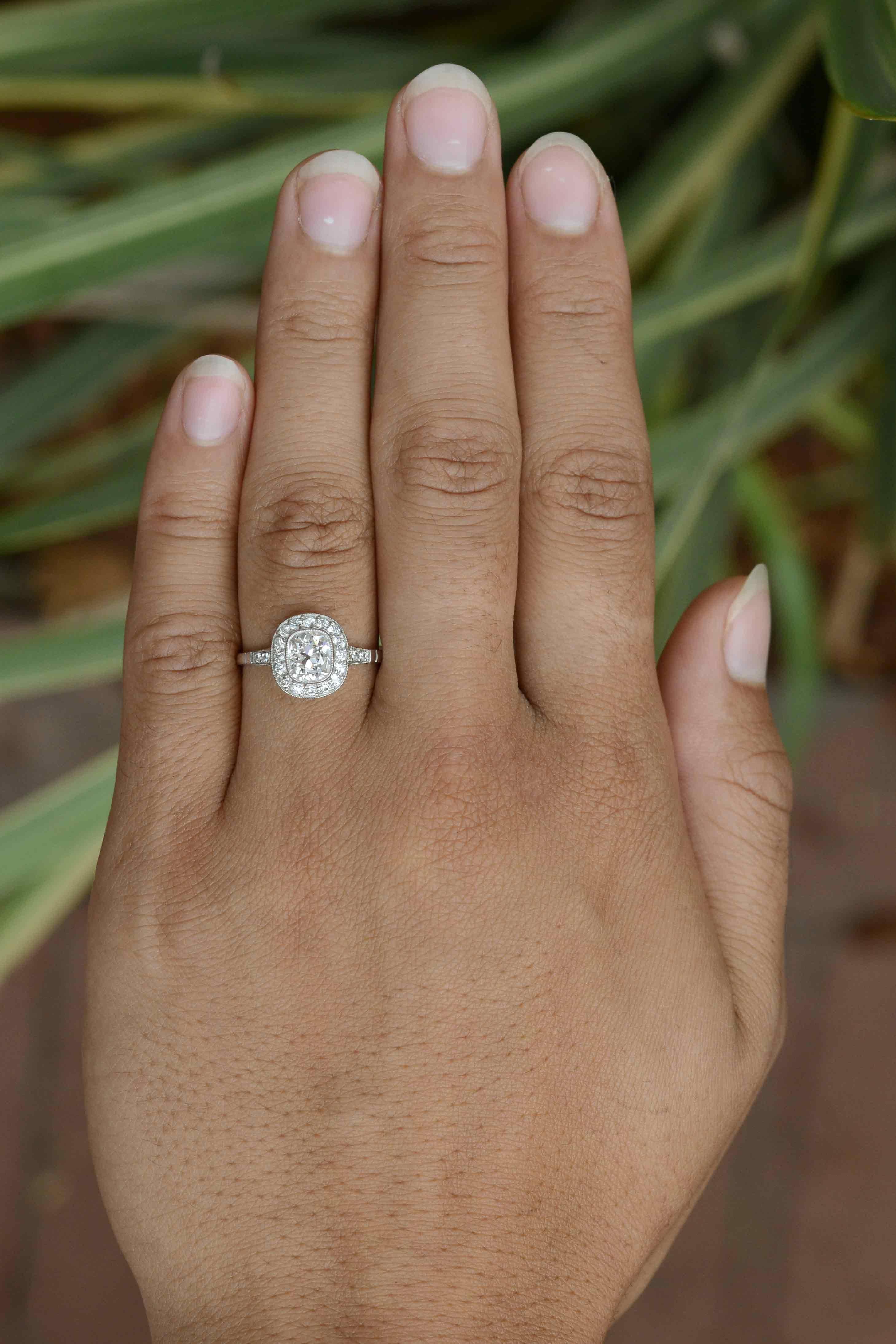 The shimmer of this over 1 carat old mine cushion diamond engagement ring is absolutely mesmerizing. Graded near colorless and blessed with fantastic clarity, the chunky facets of this beauty are brought to life in an Art Deco style halo, the bezel