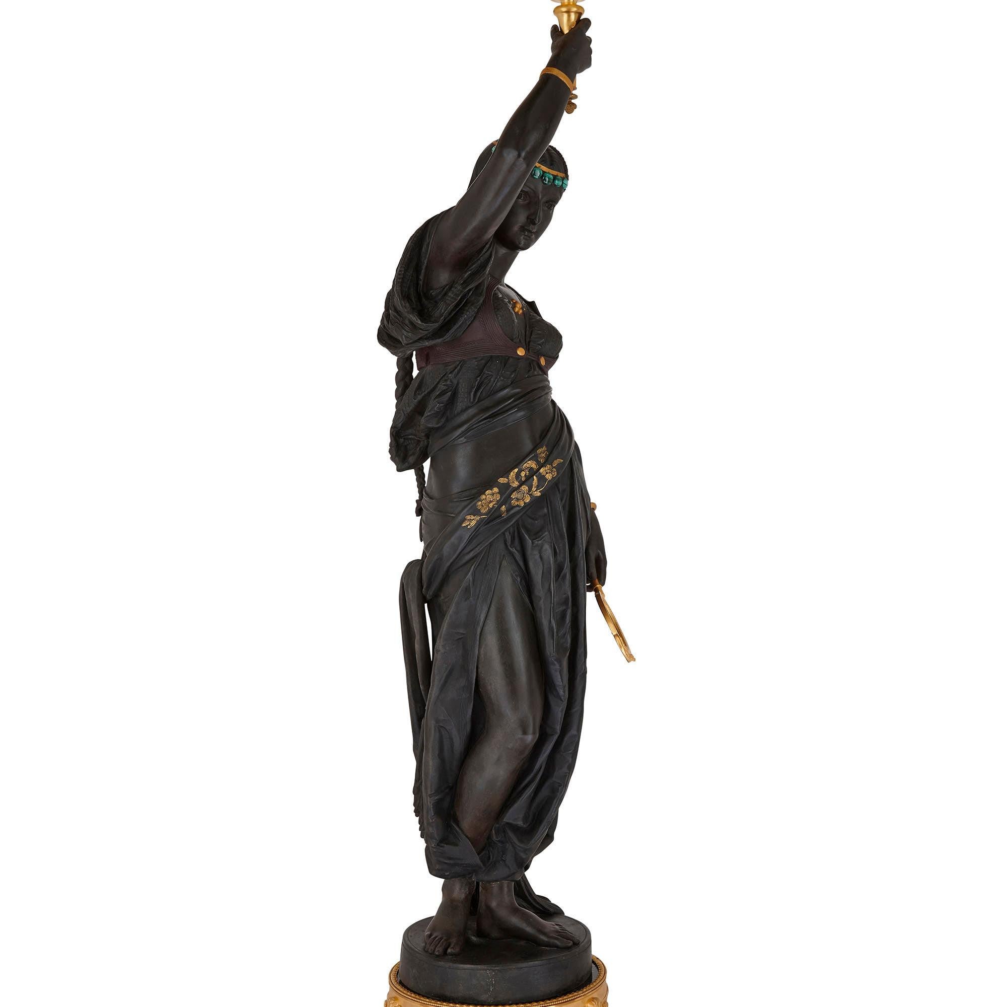 Standing over two and a half metres tall, this sculpture is truly exceptional—an unusual, and remarkable, statement piece. The sculpture features a standing female figure, her dress distinctly Orientalist in nature. She is cast from bronze, with