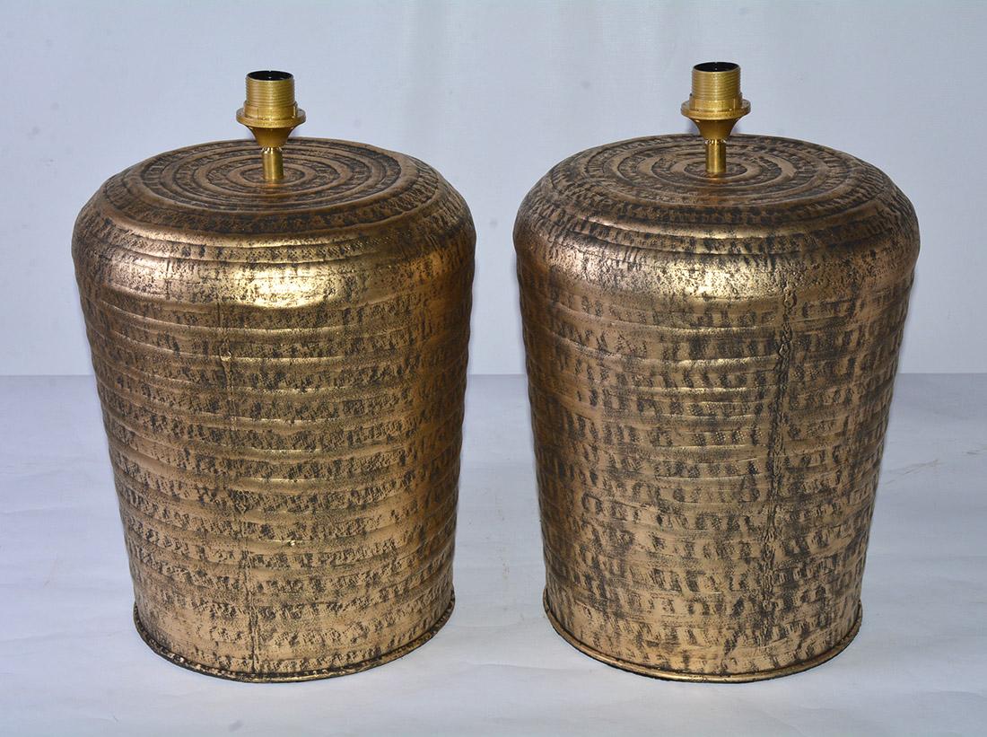 Large brass or gold colored metal jar lamp bases from India. The jar shaped lamp has textured hammered surface with ribbed trimmed details encircling the body. Hollywood Regency Indian style ginger jar form table lamps with ethnic influences.