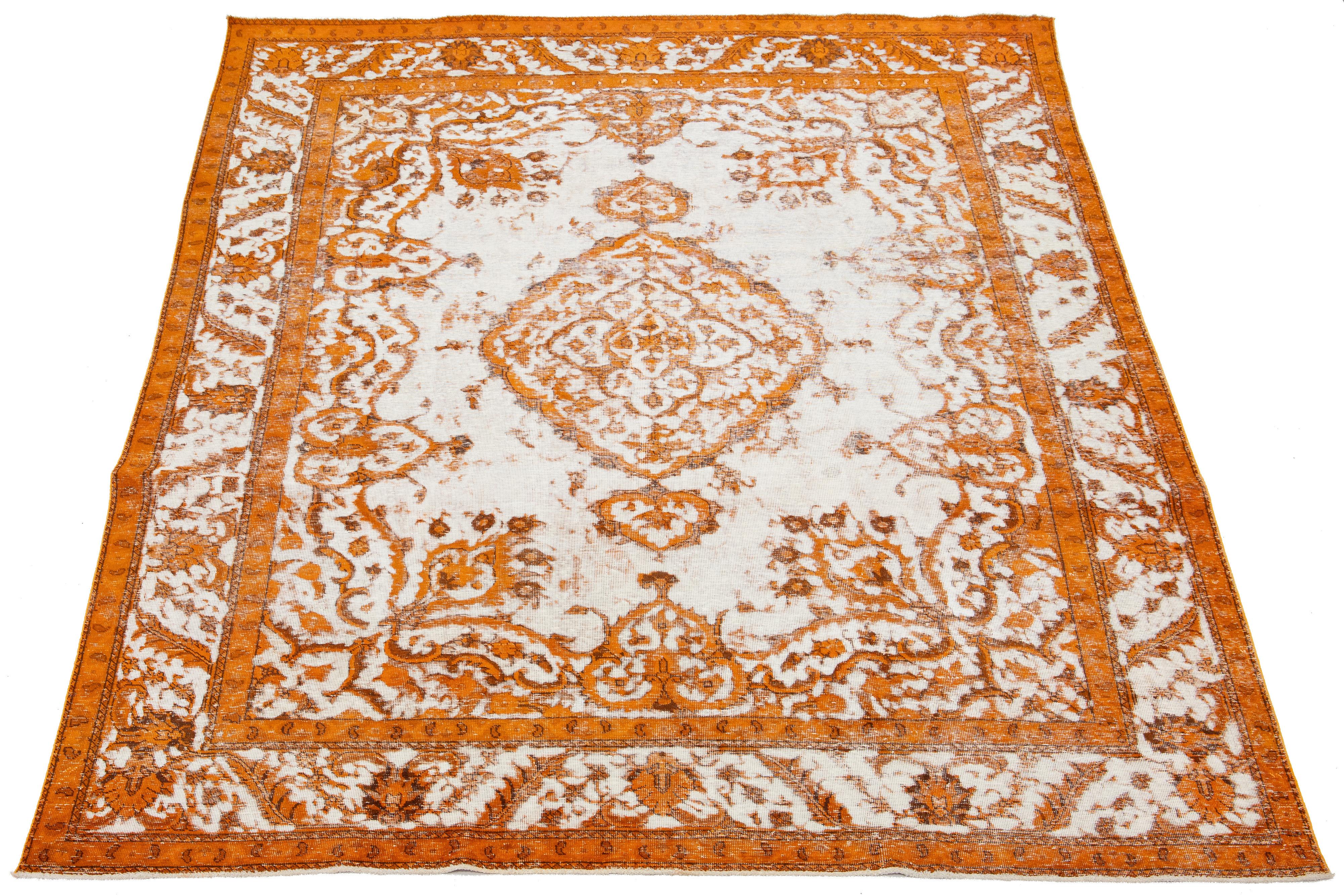 This is a Persian wool rug with an ivory base color, a medallion floral design, and orange accents. It is hand-knotted and has an antique appearance.

This rug measures 9'3'' x 12'2