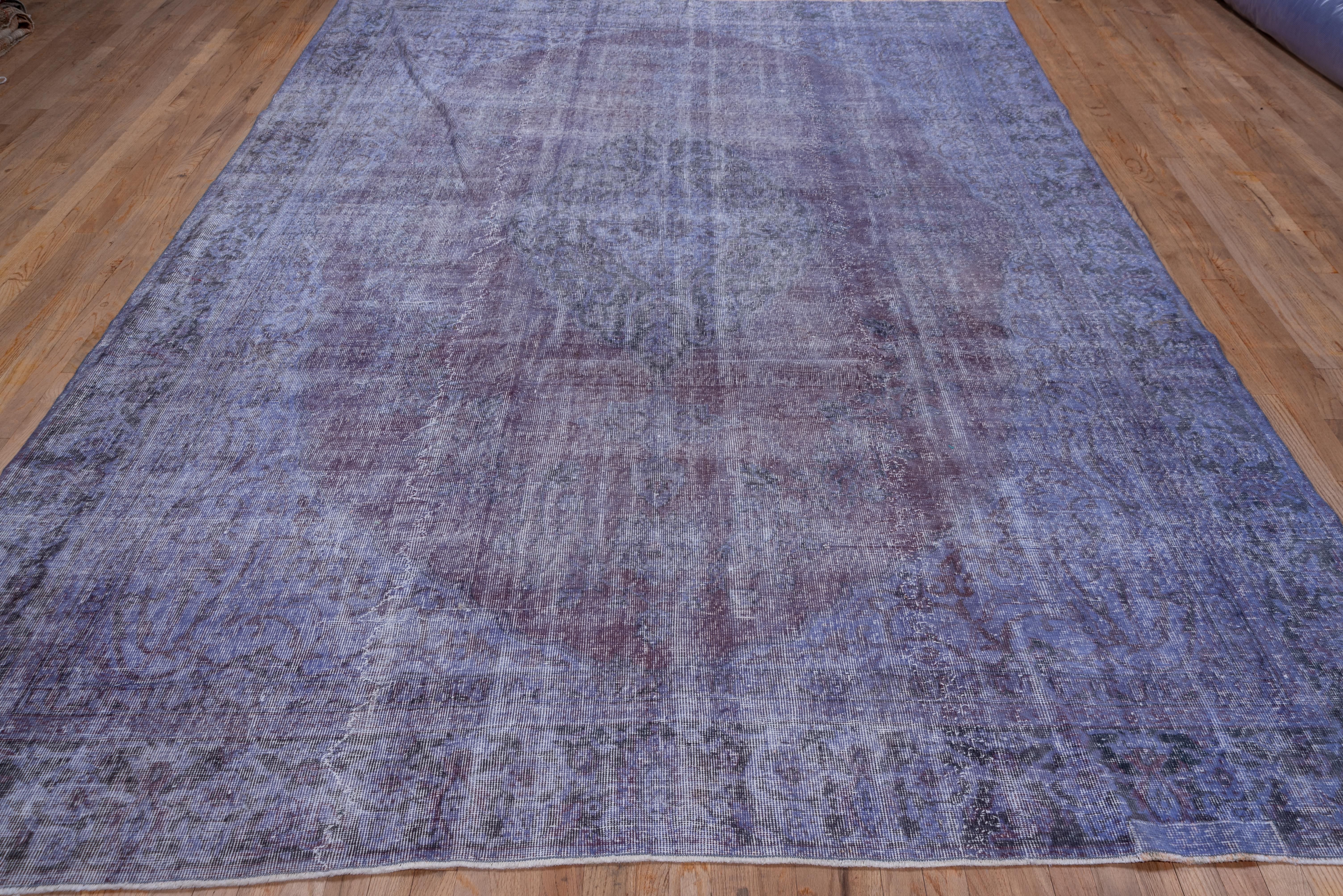 This clearly distressed carpet has been over dyed in a medium violet uniforming the original medallion and corners layout still visible on the back. The white of the foundation adds another distinct color to an otherwise monochrome palette.