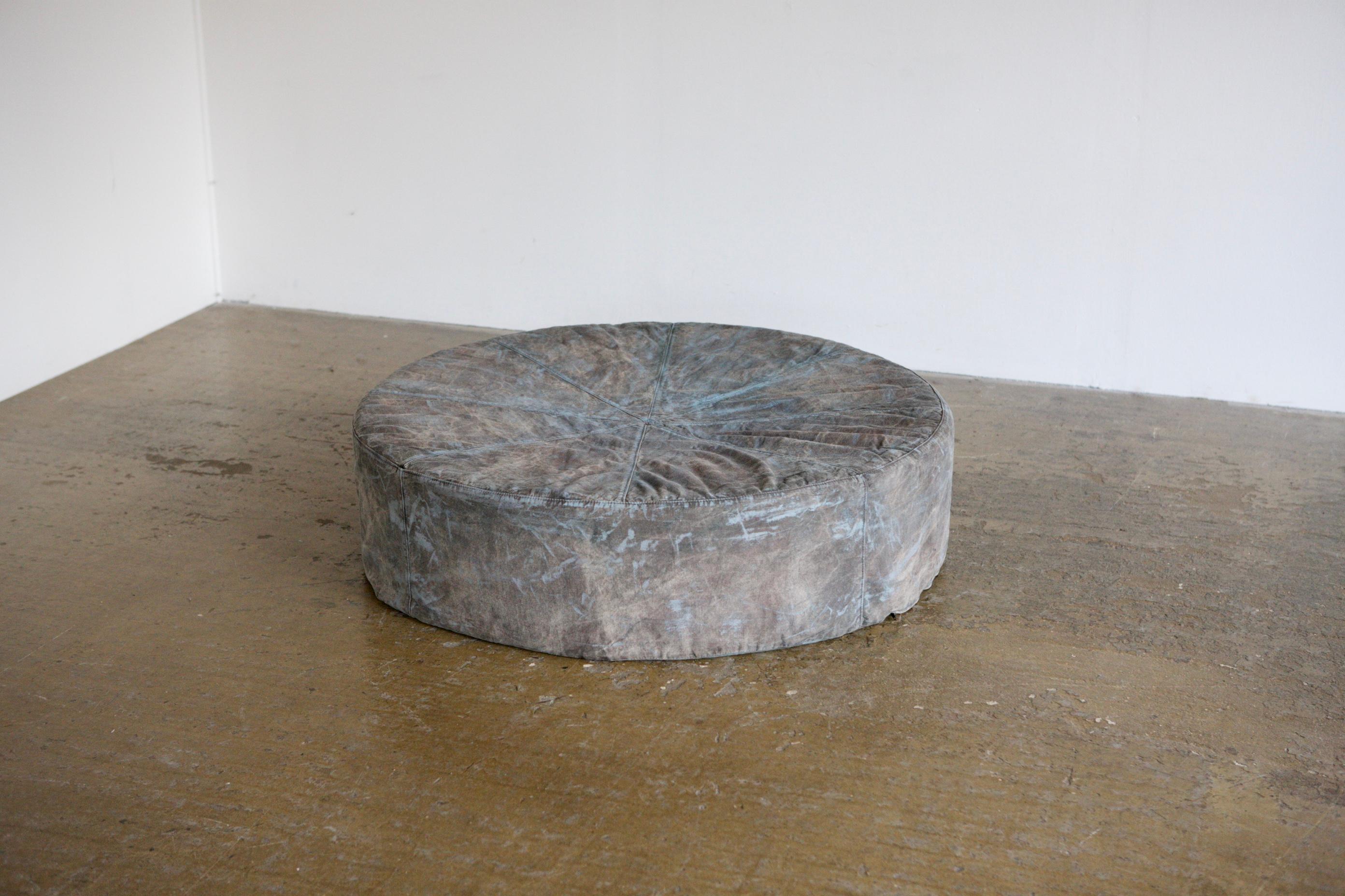 A large circular pouf with an overdyed and painted finish to demin. A great central piece that could replace a coffee tabe. Circa 1980's France.