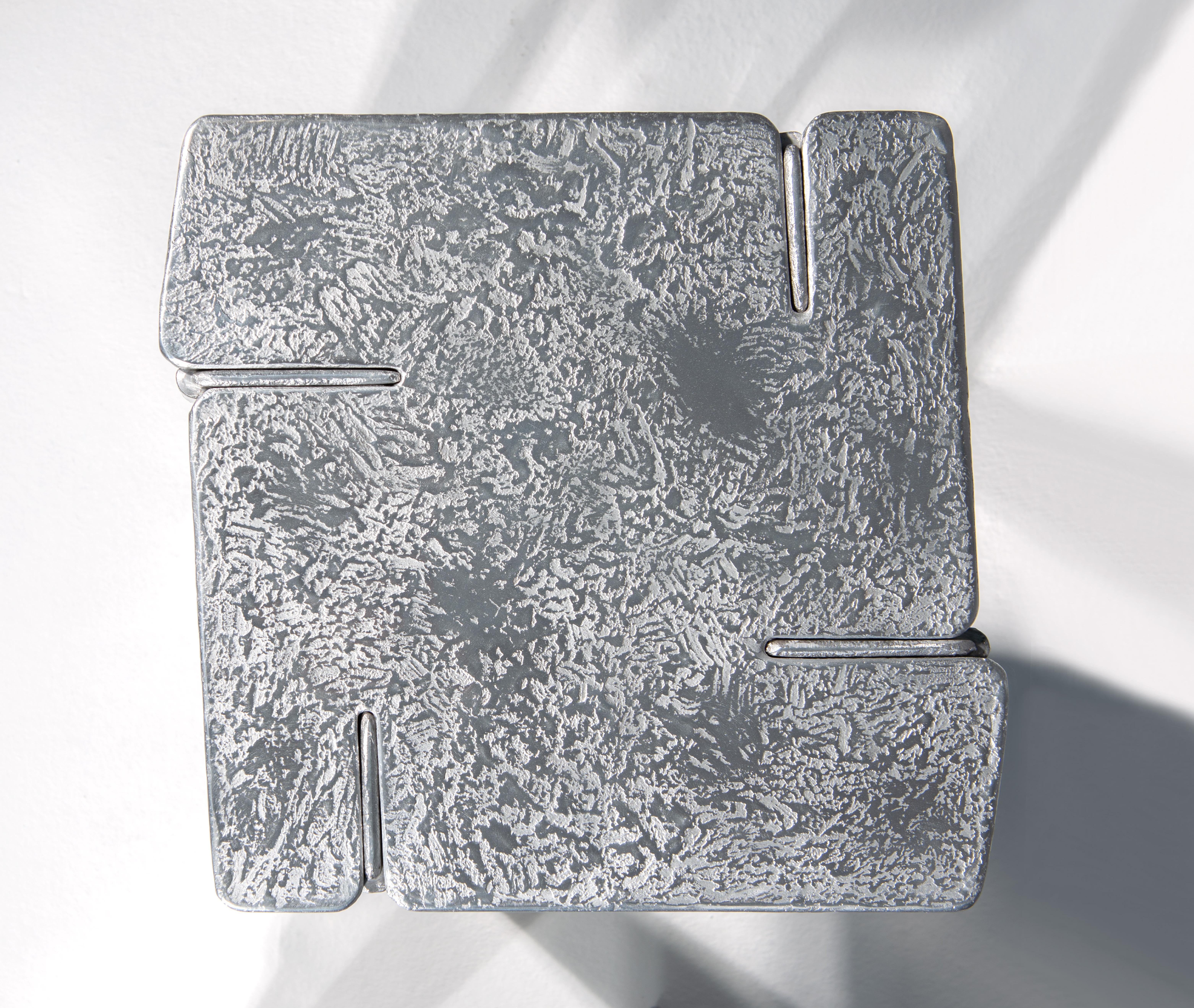 Der Couchtisch Overlap ist komplett aus Aluminium gefertigt. Es wird durch Gießen des Aluminiums in spezielle Formen aus Sand gewonnen. Das skulpturale Aussehen der Oberfläche und die Verwendung von Metall als Rohmaterial machen diesen Gegenstand zu