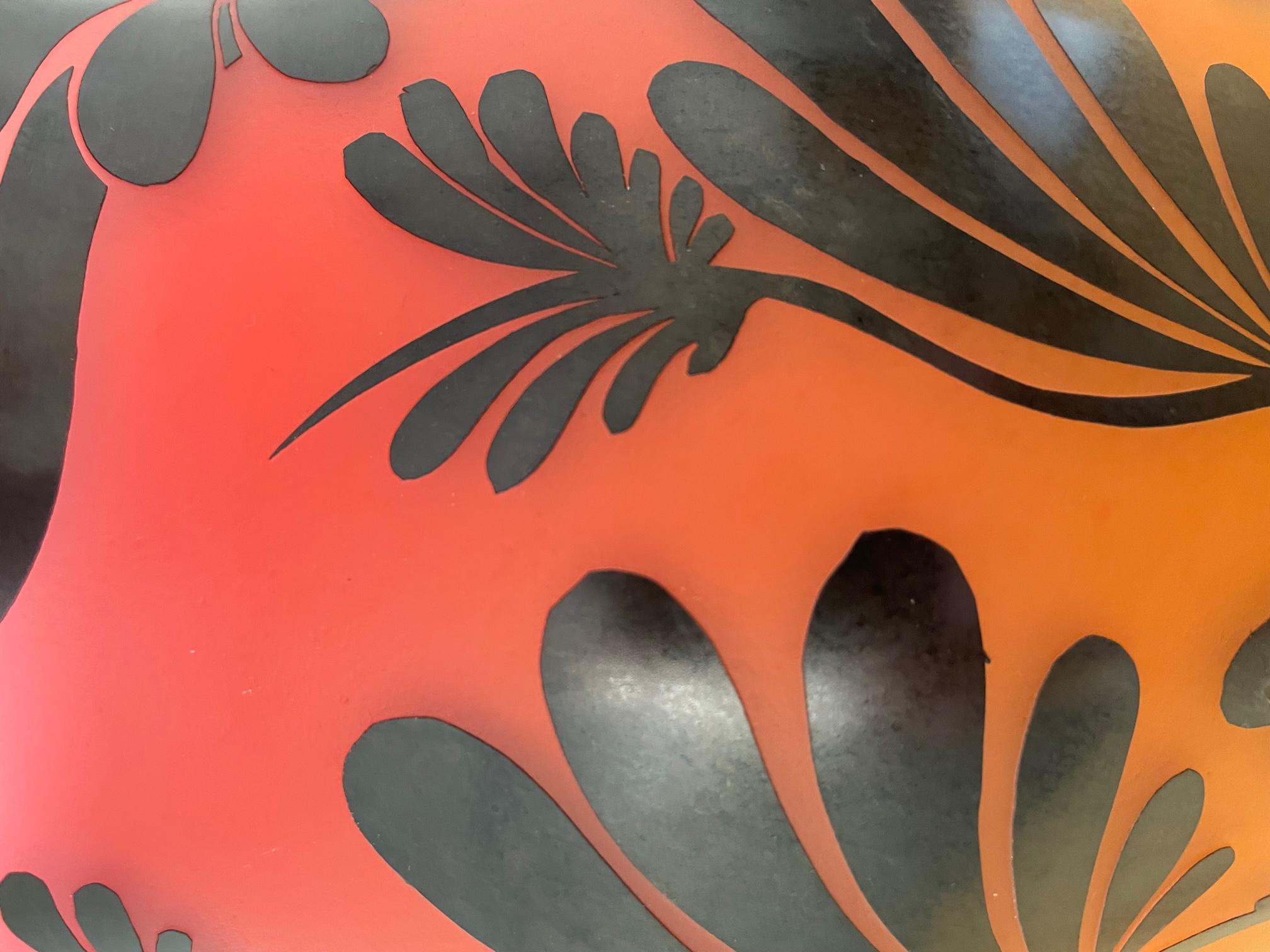 This cameo etched vessel by Gary Genetti is overlay blown glass. It features red to gold color fade background to enhance the graphic black overlay. The original artwork is drawn on the piece, hand cut then pressure etched through layers of color to
