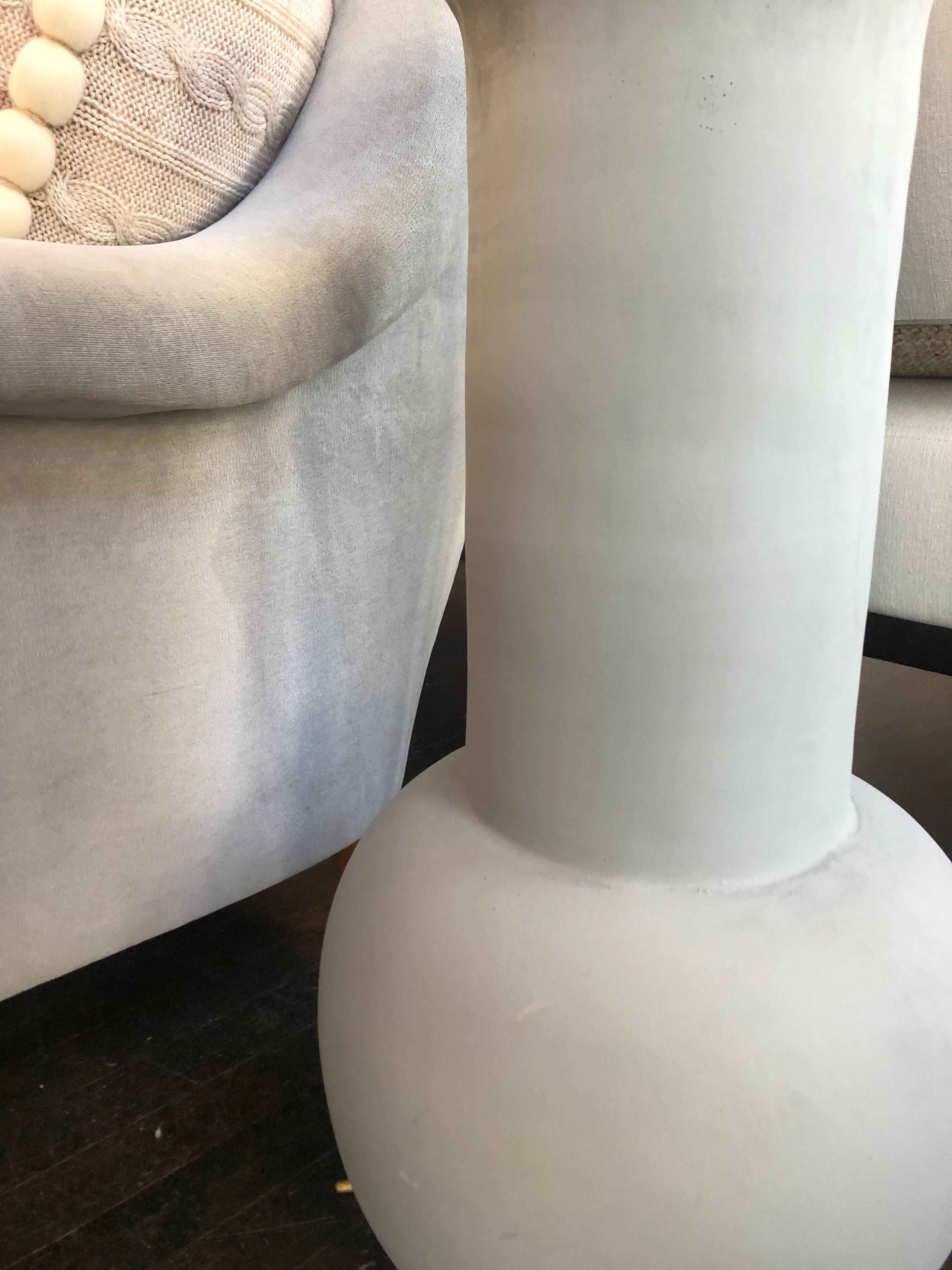 Modeled on a Classic urn/vase shape from antiquity, this vase is produced in a molded resin which is infused with either grey or white pigment color. Holds water and can be used indoors or outdoors. Made in USA.