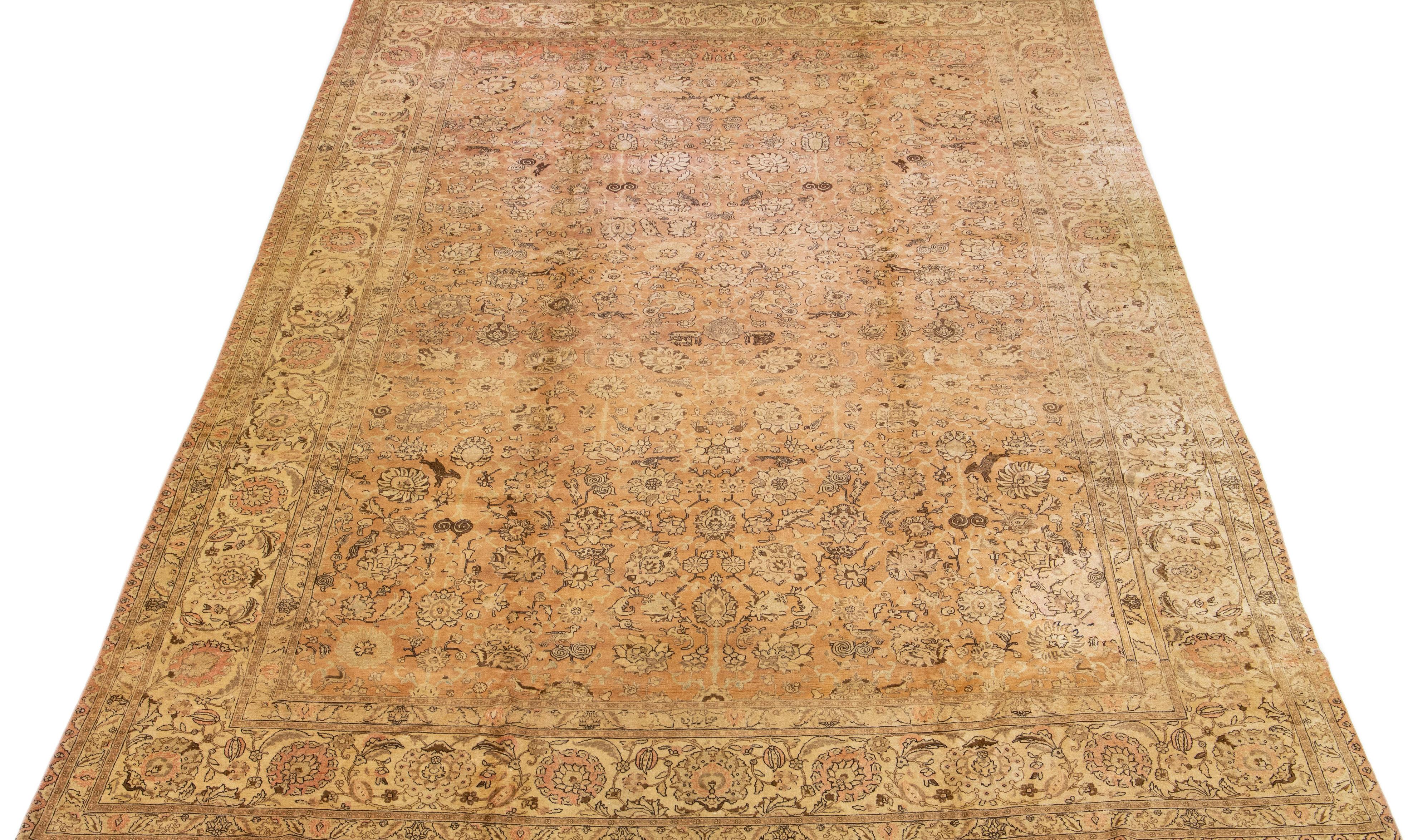 This Persian Tabriz wool rug showcases an exquisite traditional floral medallion design with a striking tan accent against a beige, blue, and brown background. 

This rug measures 12'7