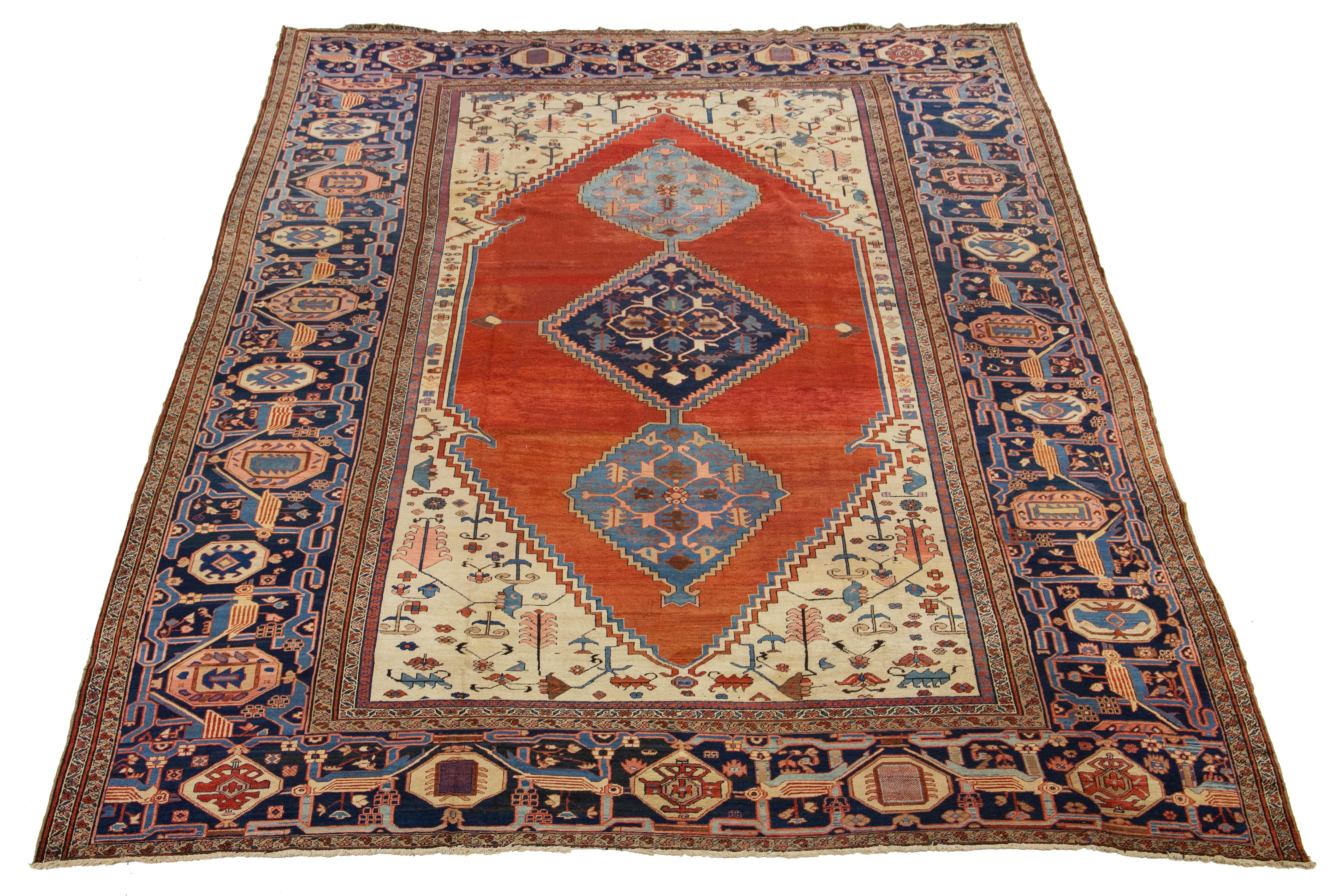 This Bakshaeish Persian hand-knotted rug showcases a stunning rust and beige field, highlighted by a vibrant array of multicolored accents intricately woven into an enchanting all-over floral design, framed by a navy blue border. It is ideal for