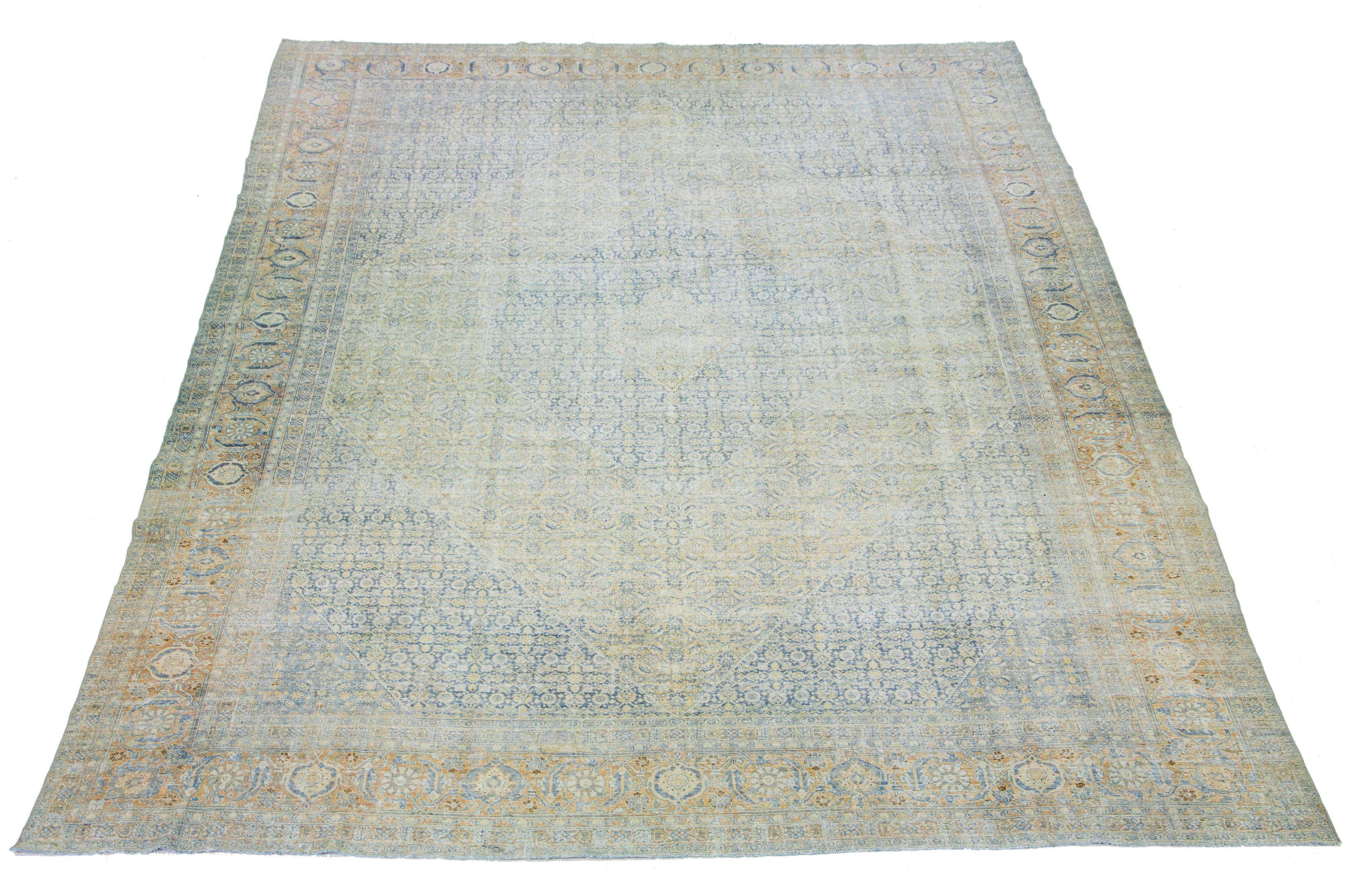 1900s Persian Tabriz wool rug, handcrafted, showcases a traditional floral pattern. The contrast between the light blue backdrop and the yellow, beige, and brown emphasizes the design.

This rug measures 12'7