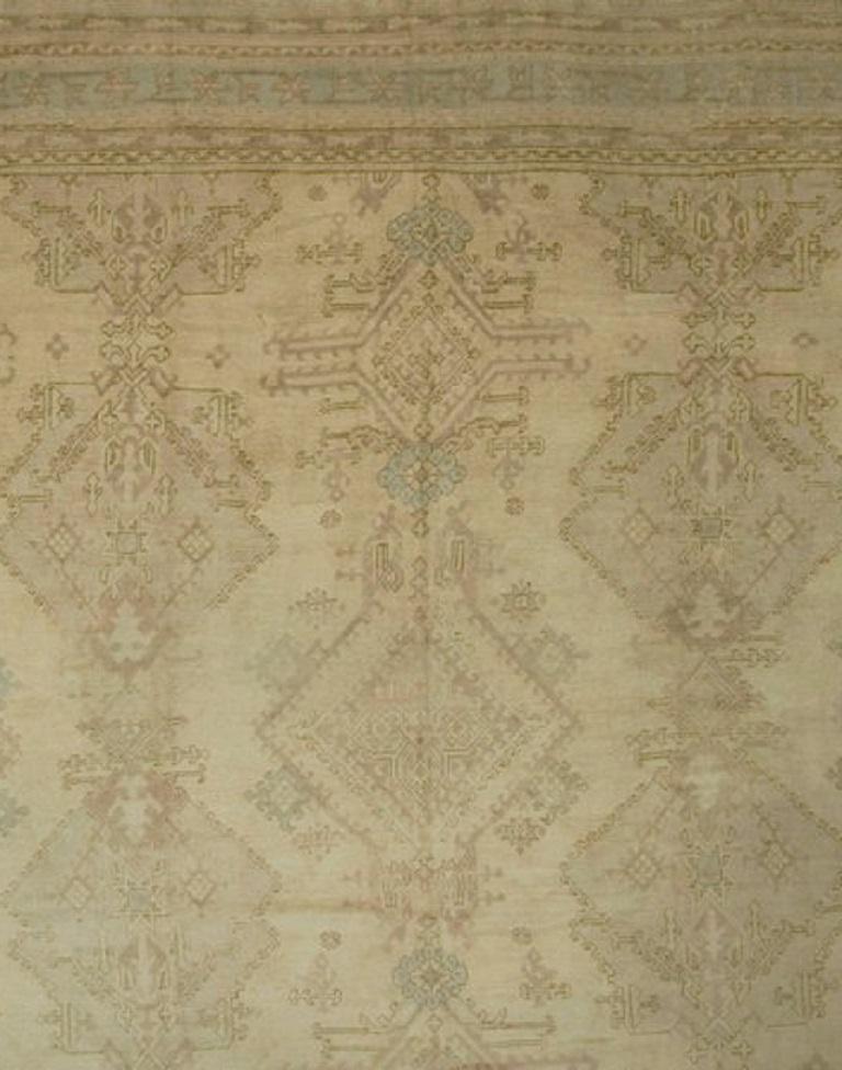 15'2 x 21'7. This pattern on a cream ground is descended directly from the 18th Century Oushak's. Three and a half columns of complex enormous palmettes and elaborate diamond shapes fill the field. The half column at the right is unusual in that