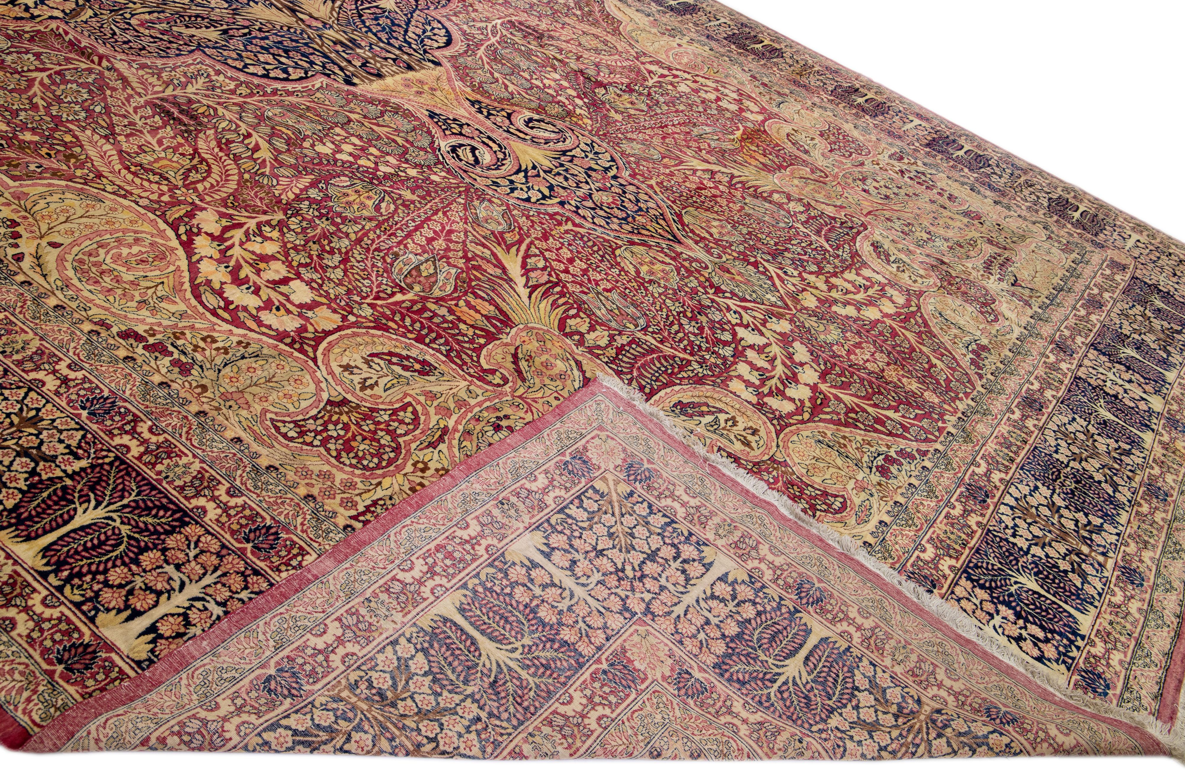 Magnifique tapis antique Kerman en laine nouée à la main avec un champ beige et rose. Ce tapis persan a un cadre bleu et des accents multicolores dans un magnifique motif de rosettes.

Ce tapis mesure : 14'11