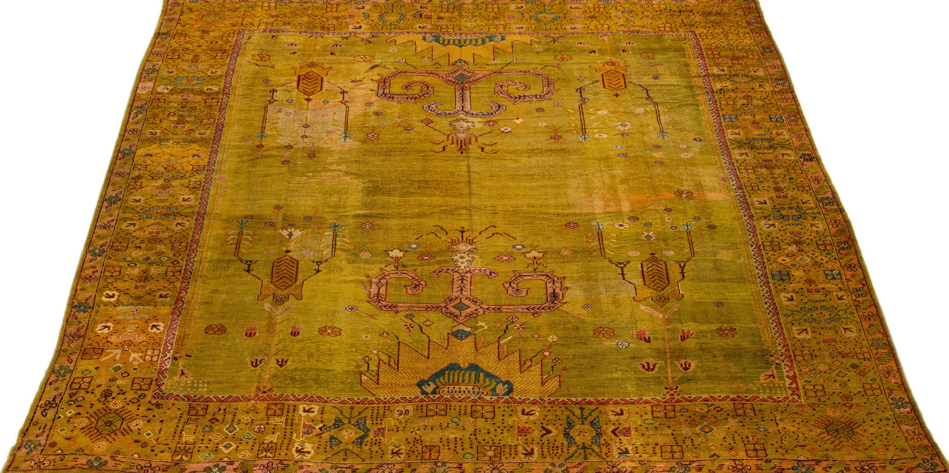 This exquisite hand knotted square wool rug from the 19th century Turkish Oushak collection features a stunning olive-yellow color field, complemented by elegant blue and rust accents arranged in a striking large scale floral pattern.

This rug